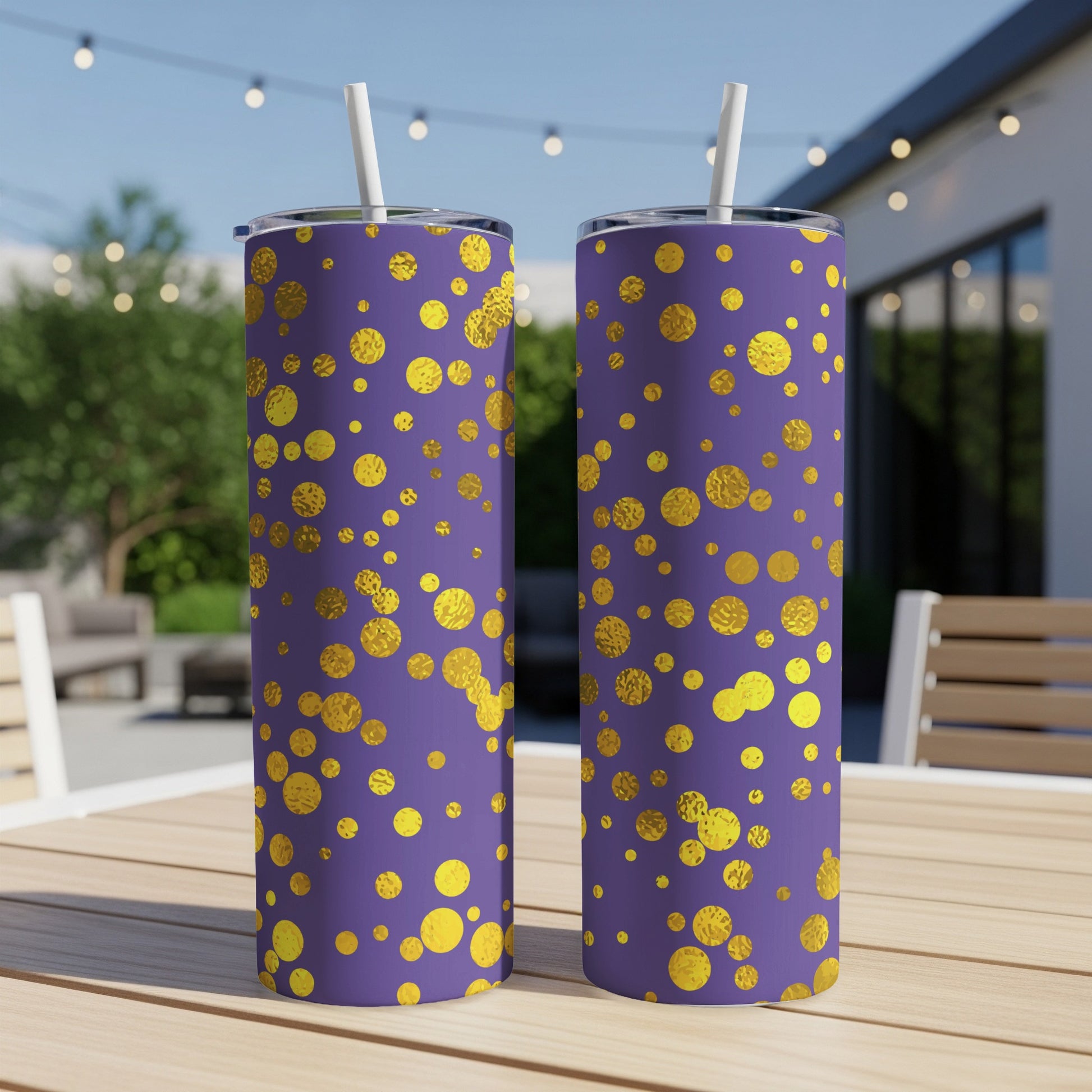Two purple tumblers with gold polka dot pattern and white straws on a wooden table.