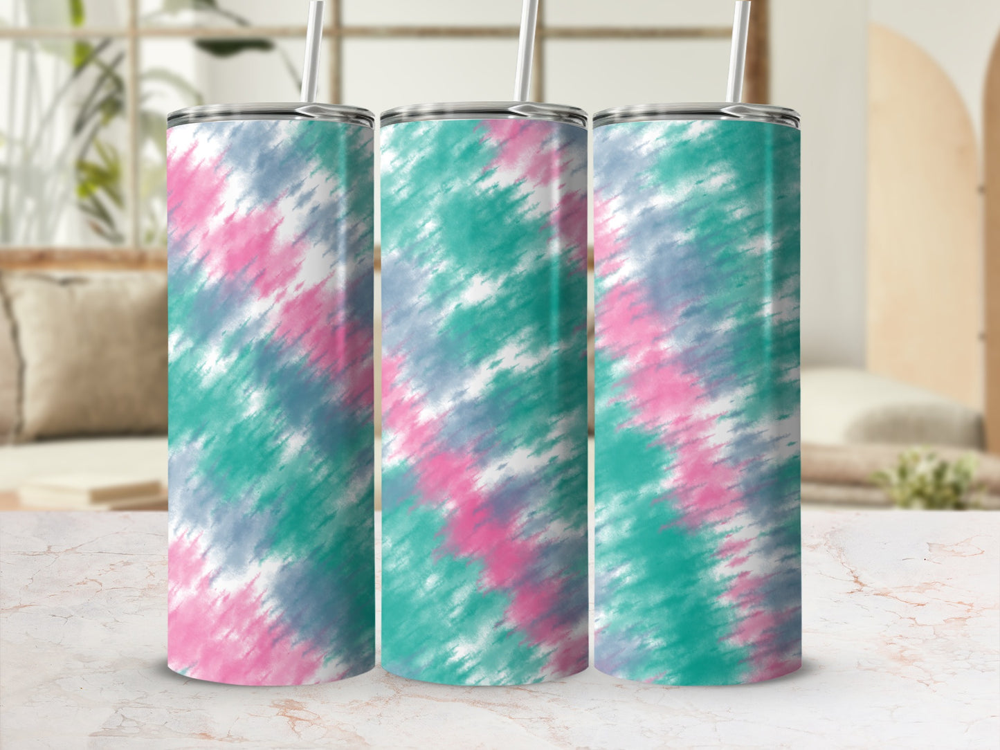 Three tumblers with a pink, teal, and grey tie-dye pattern and straws.