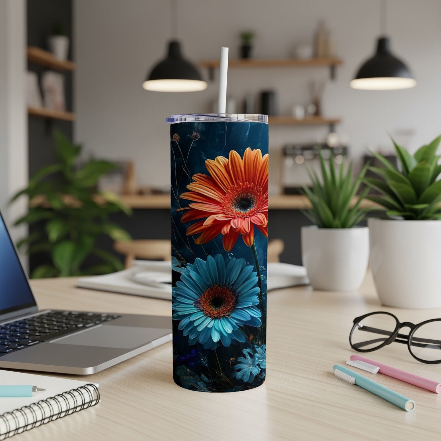 Orange and blue gerbera daisies on a dark navy background adorn a white tumbler.
