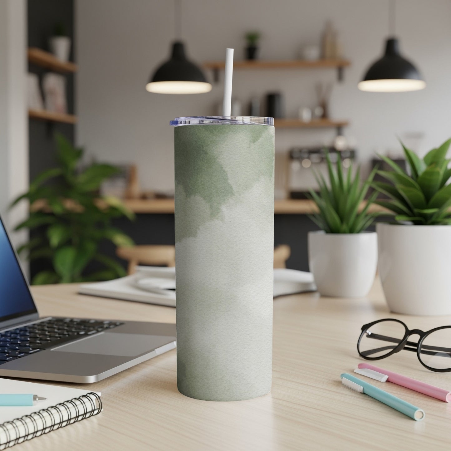 Green watercolor tumbler with straw on a desk next to a laptop.