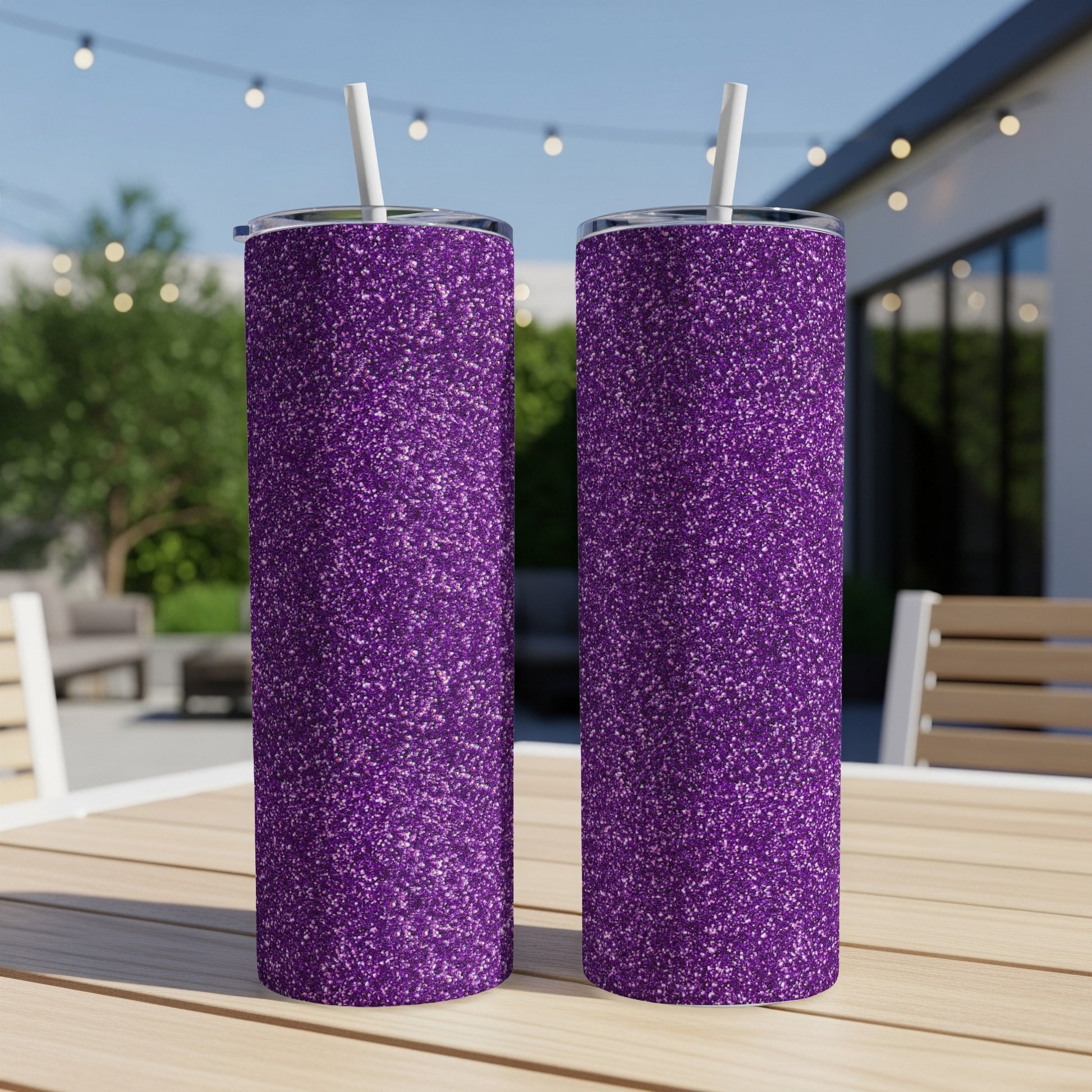 Two purple glitter tumblers with white straws on a wooden table.