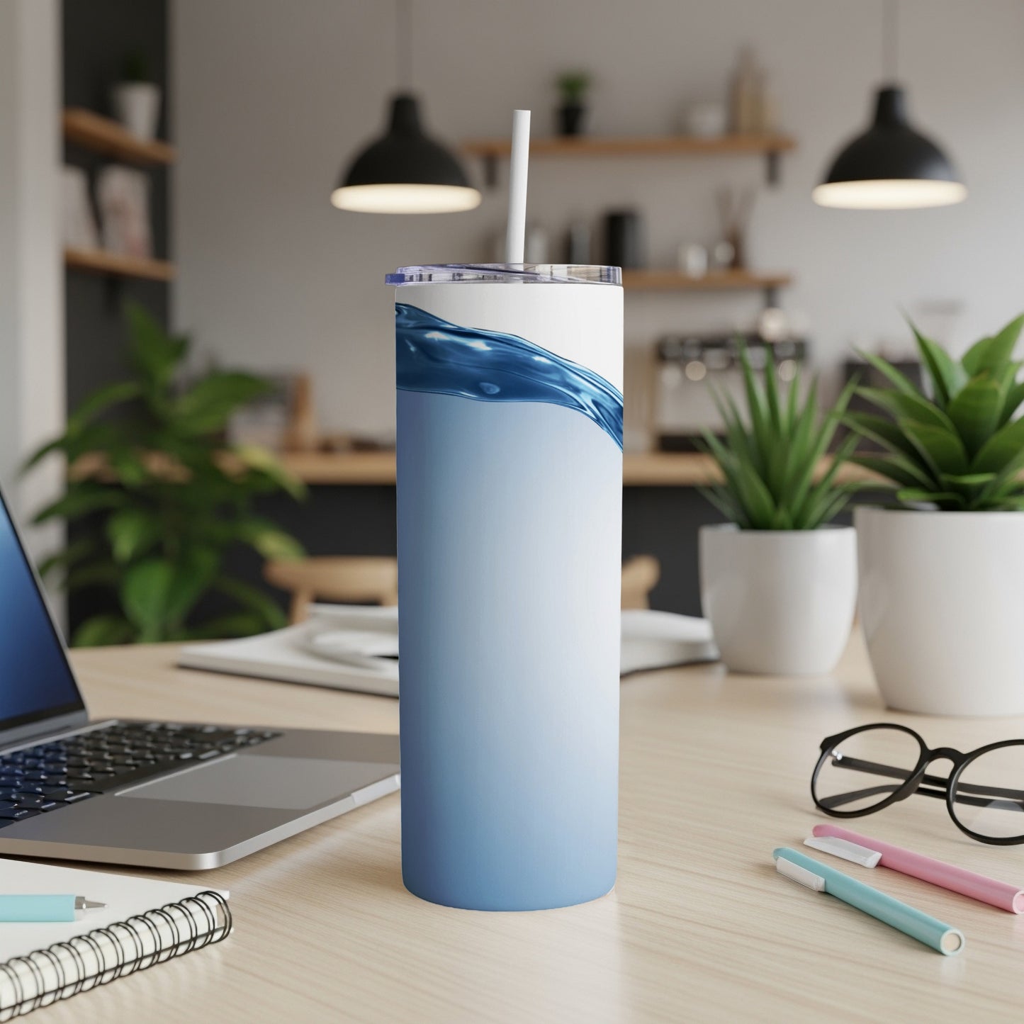 Blue wave design on a white tumbler with straw on a desk.