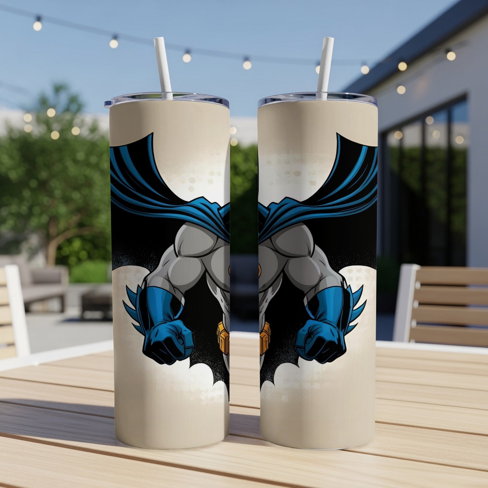 Two tumblers featuring Batman artwork standing on a table outdoors.