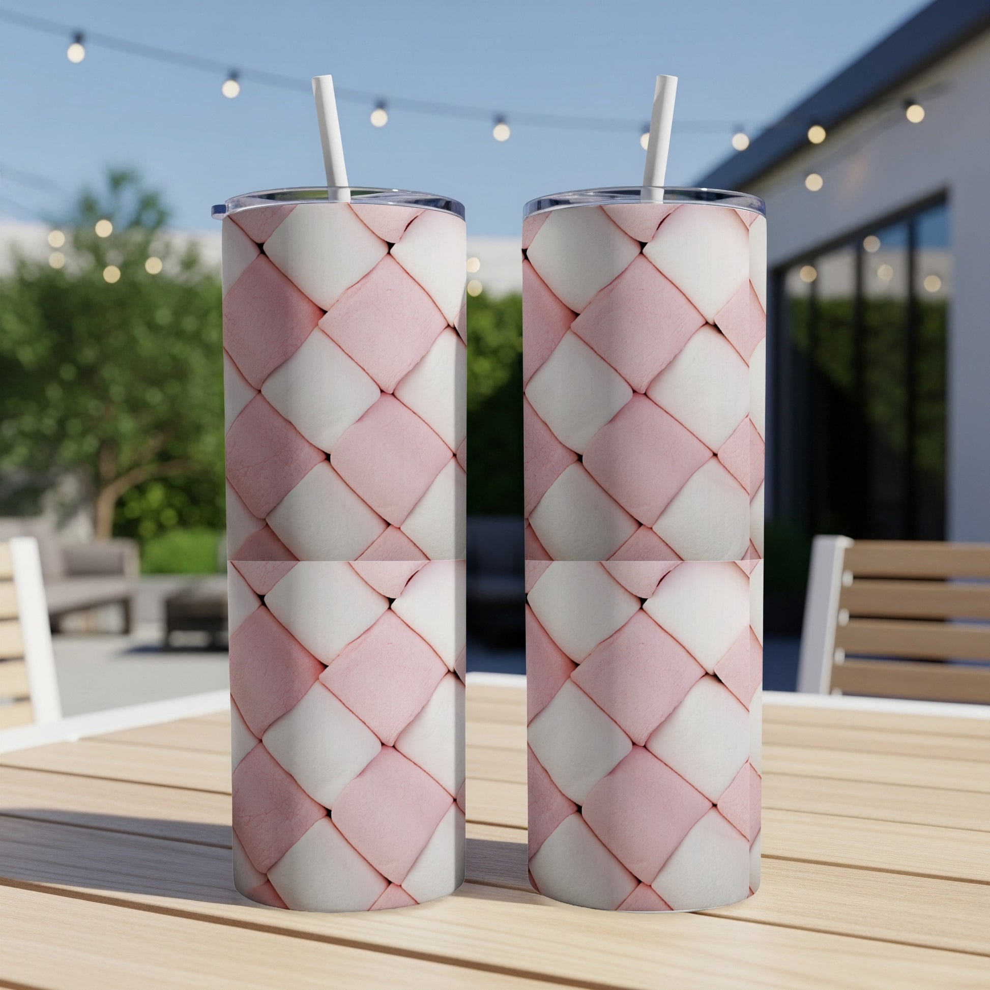 Two pink and white quilted tumblers with straws on a wooden table.