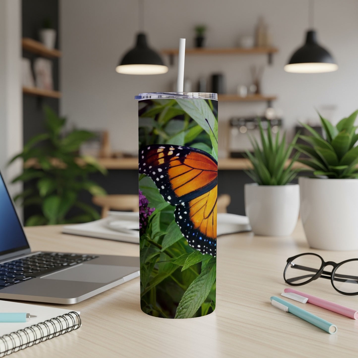 Monarch butterfly on purple flower, resting on a desk with laptop.