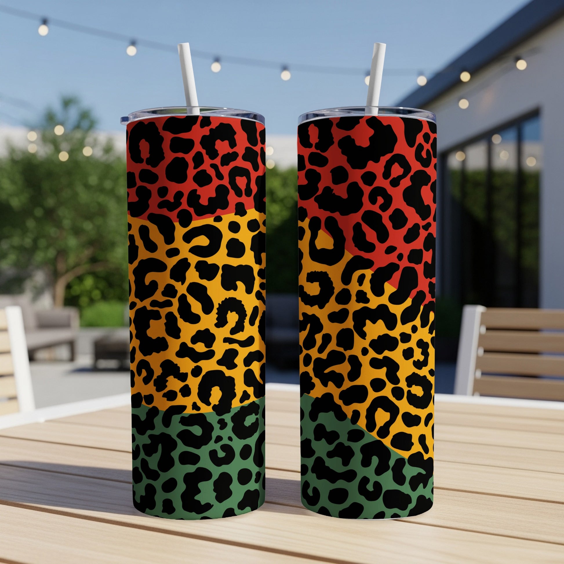 Two tall tumblers with leopard print in red, yellow, green, and black on a table.