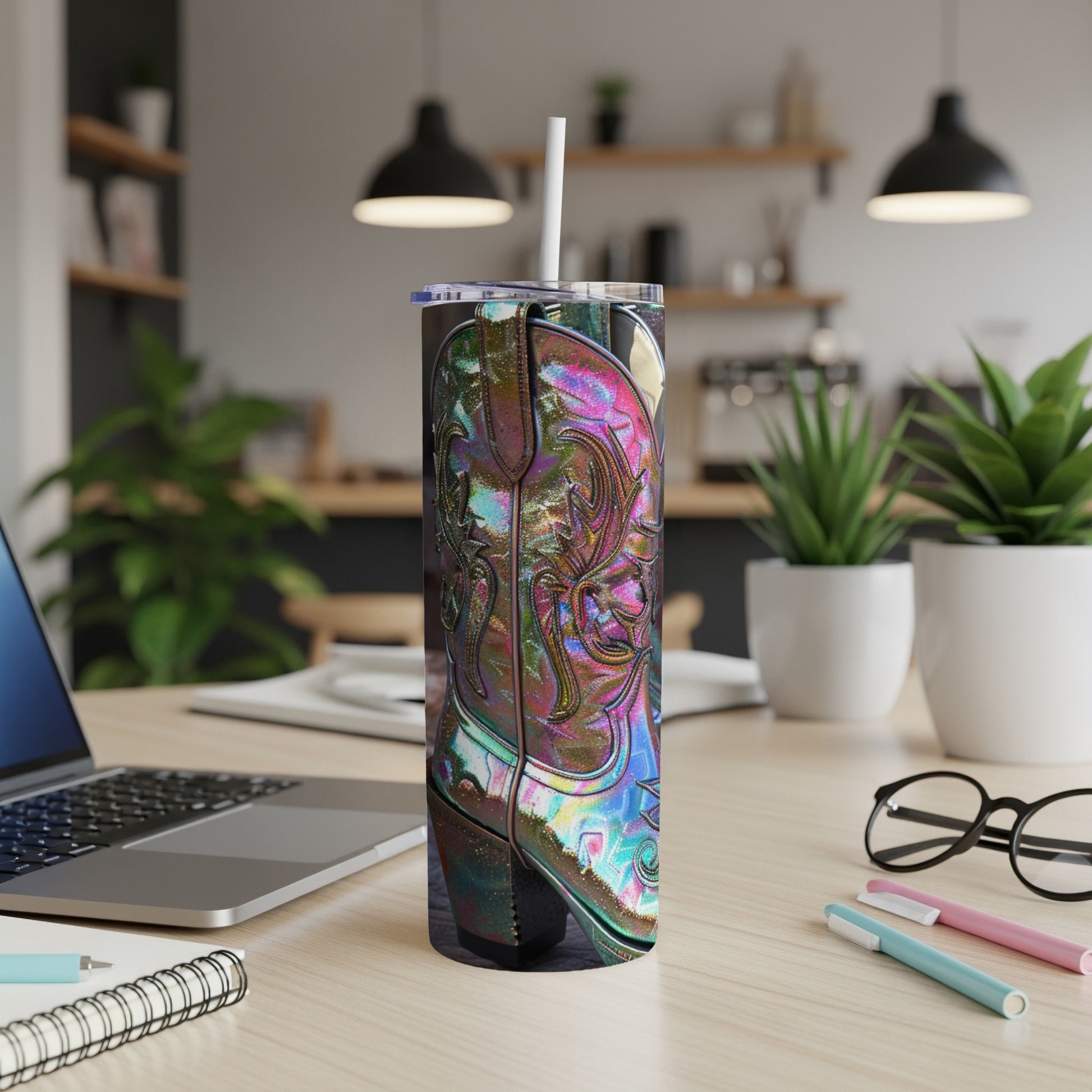 Tall, iridescent cowboy boot tumbler with straw on a desk.