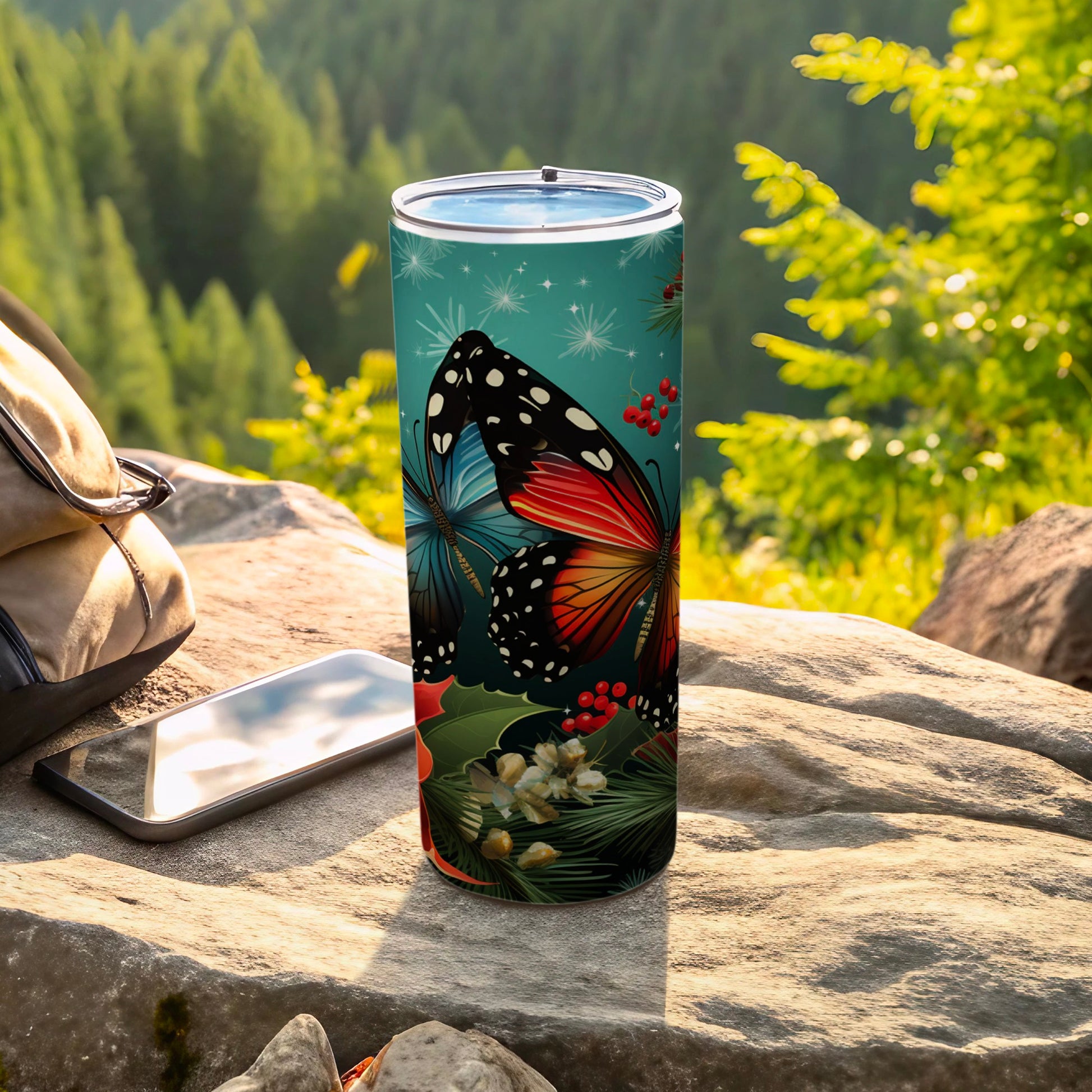 Butterfly design tumbler on a rock with a backpack and phone.