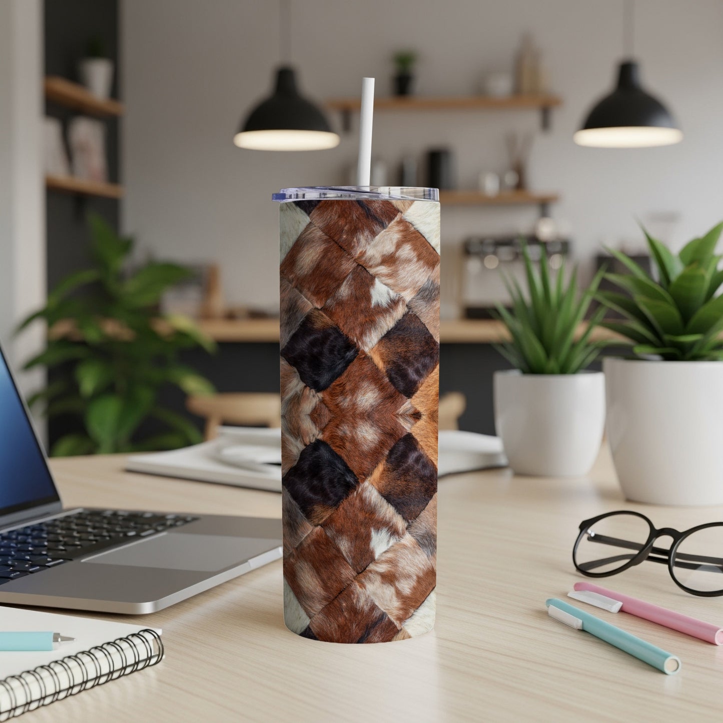 Brown and white patterned tumbler with straw on desk.
