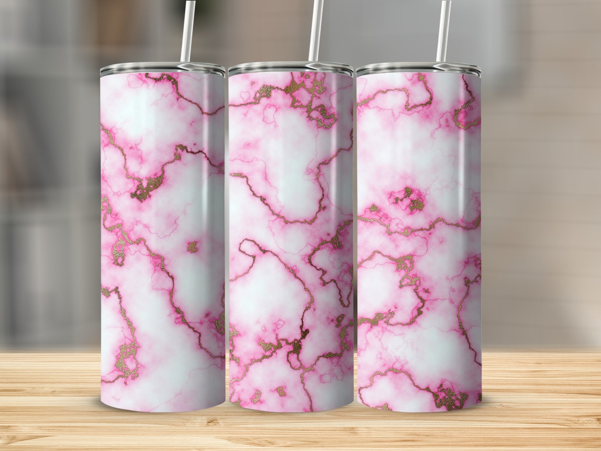 Three pink and white marble tumblers with gold veining on a wooden surface.