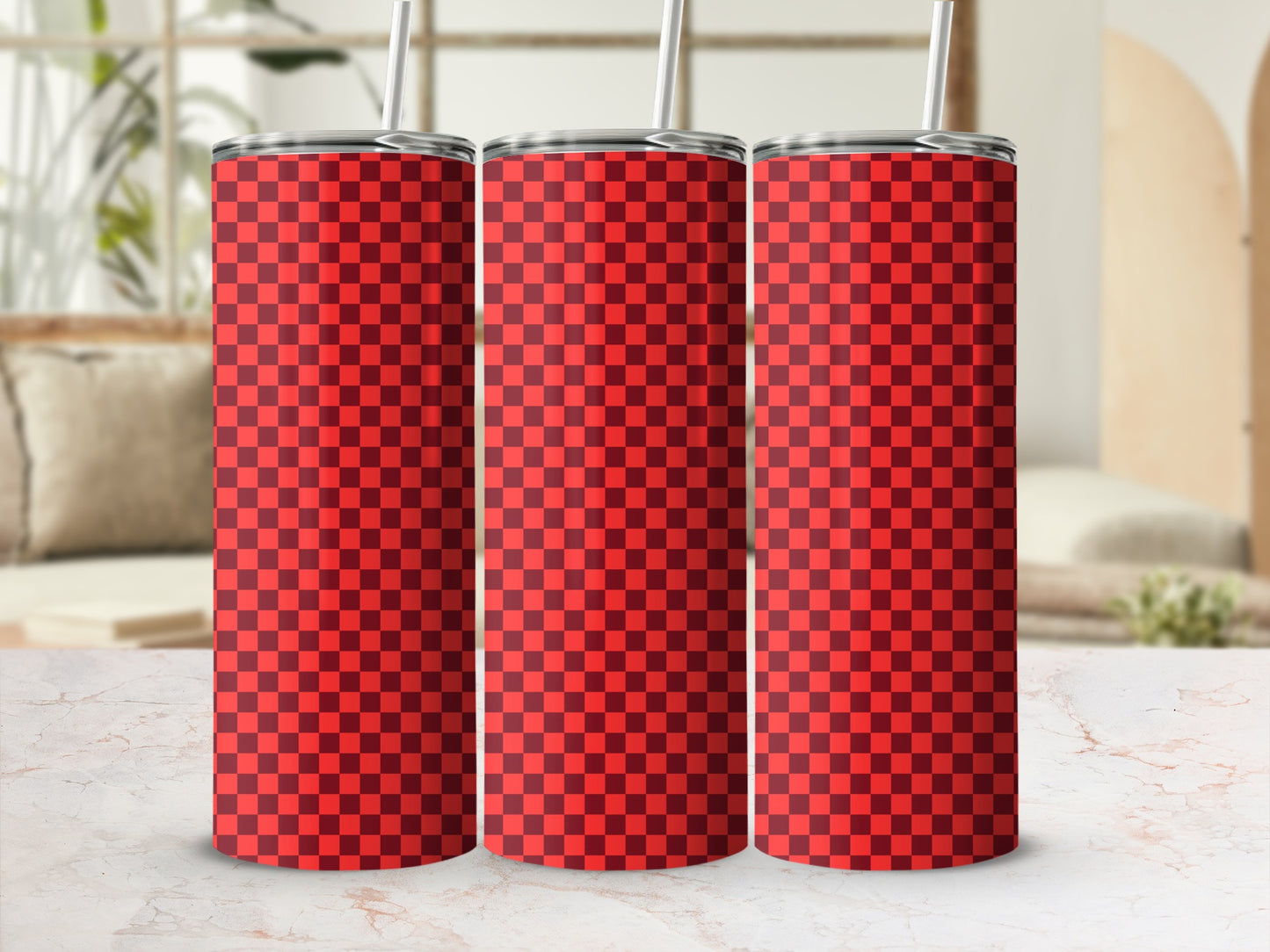 Three red checkered tumblers with straws on a marble surface.