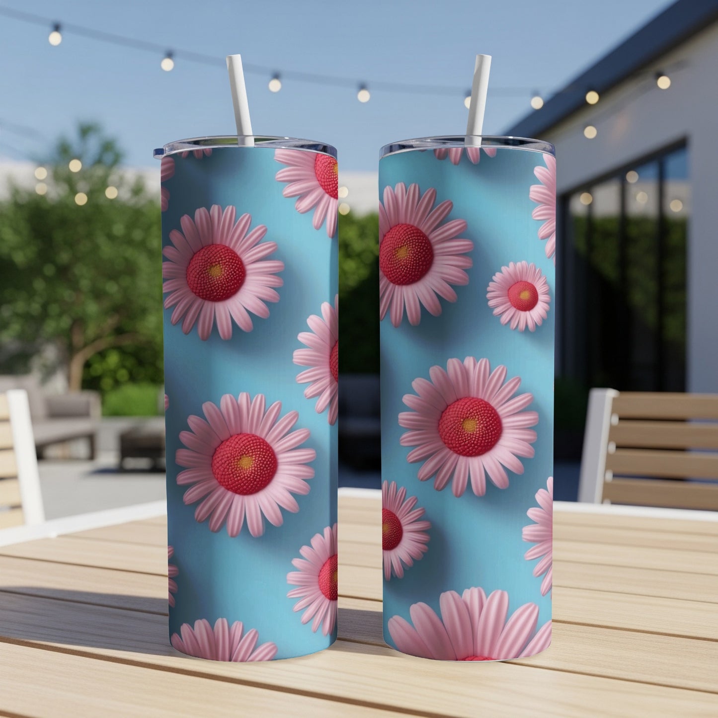 Two pink daisy pattern tumblers with straws on a wooden table.