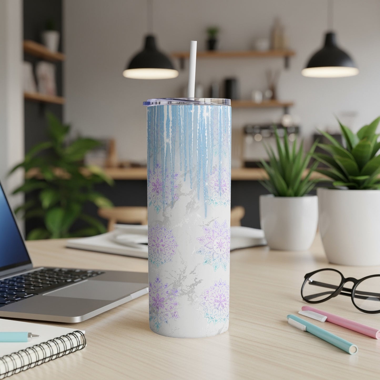 Blue and purple snowflake pattern tumbler with a white straw on a desk.