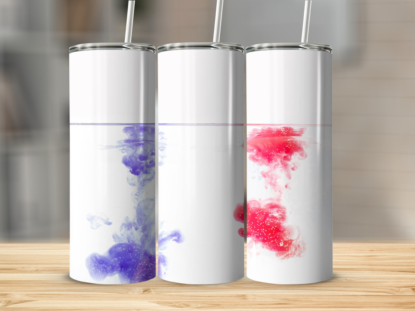 Three tumblers with colorful ink swirling in water.