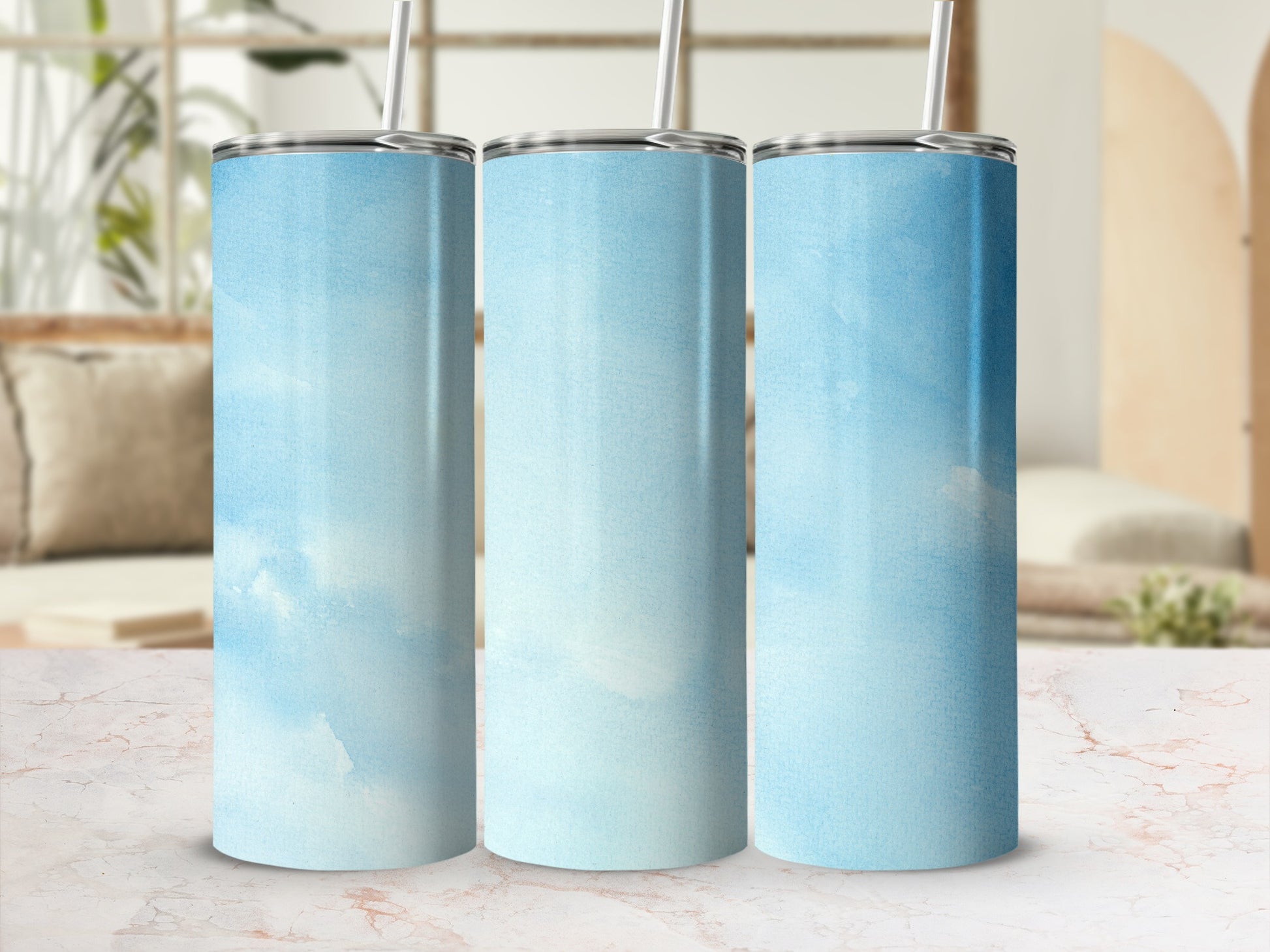 Three tall, blue sky patterned tumblers with straws.