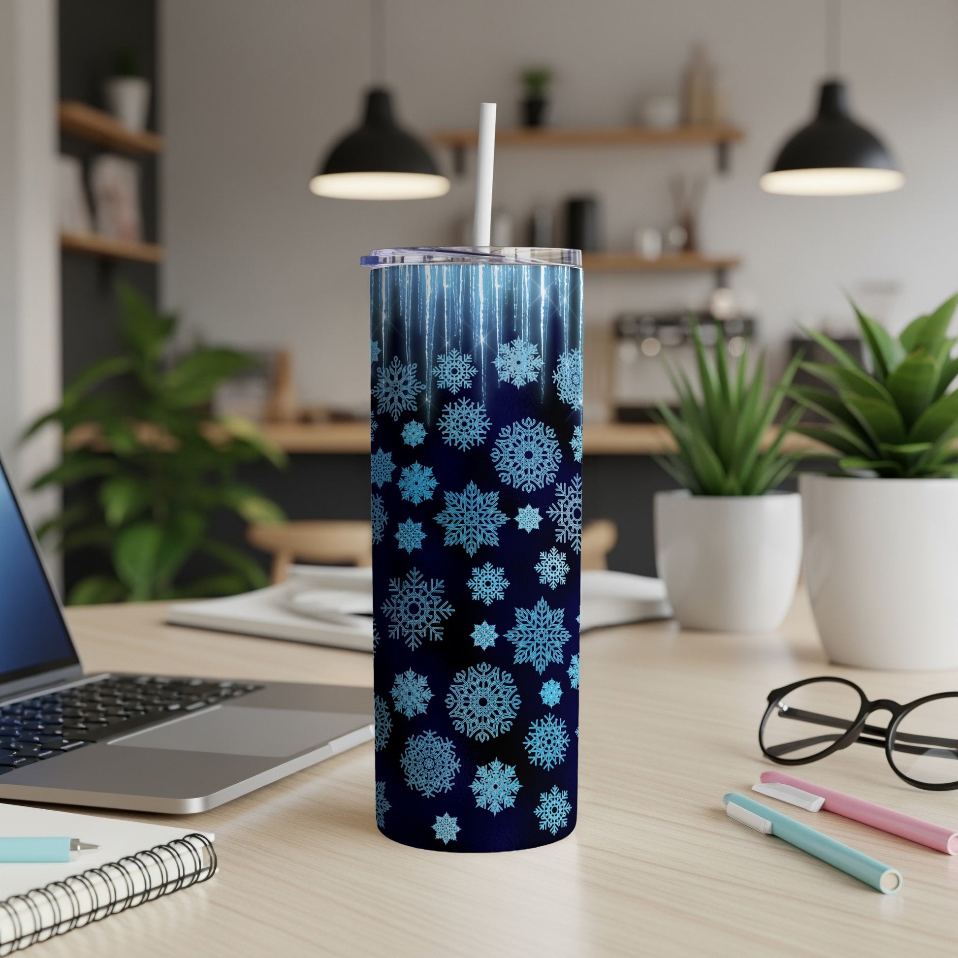 Blue snowflake patterned tumbler with white straw on a desk.