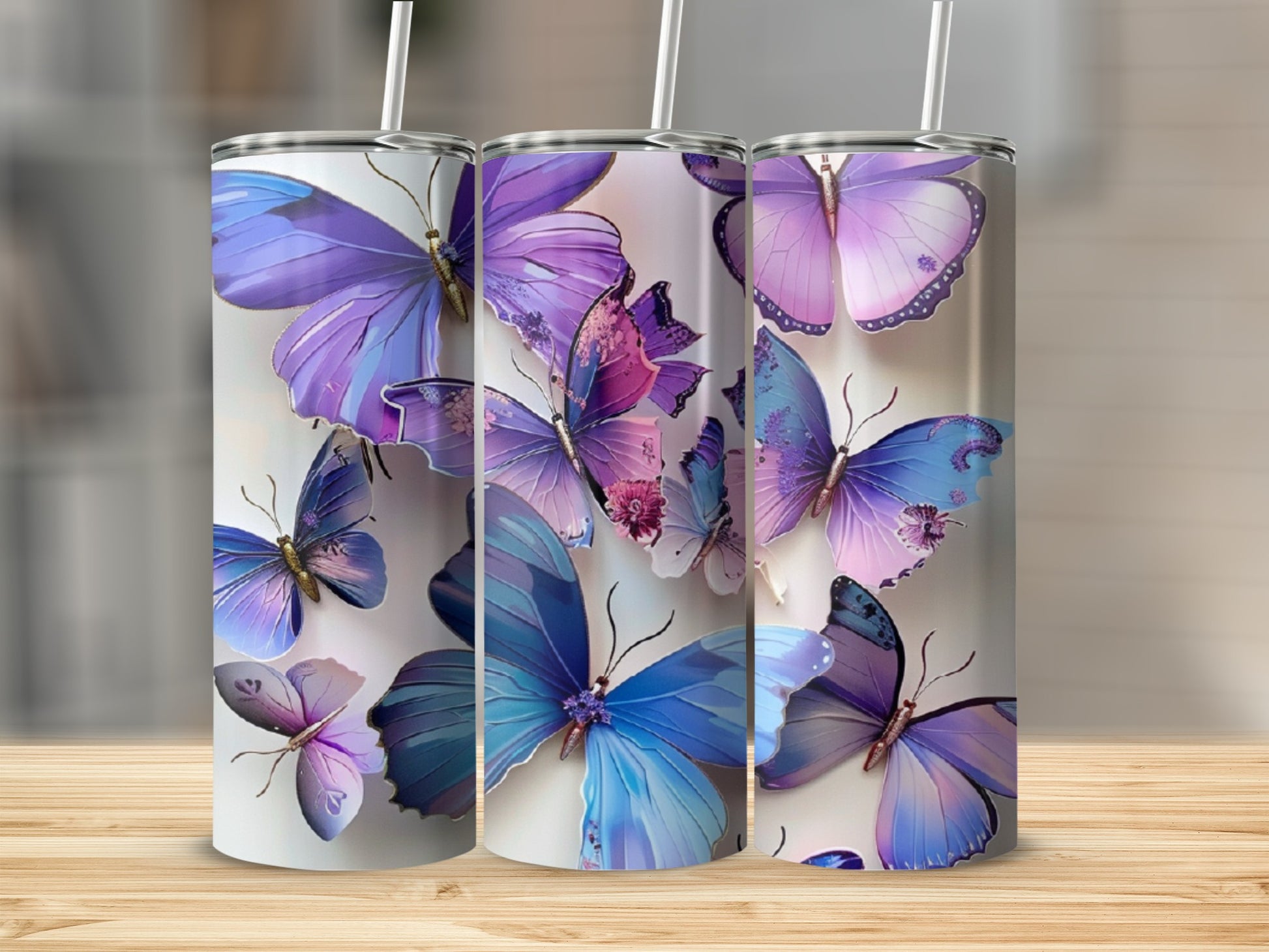 Three stainless steel tumblers with purple and blue butterfly designs.