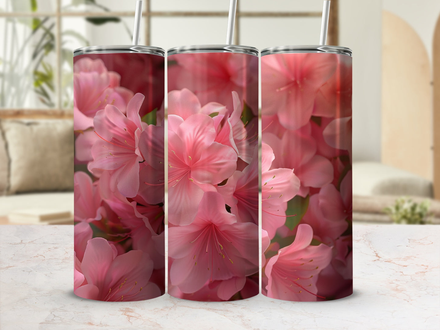 Three pink floral tumblers with straws on a marble surface.