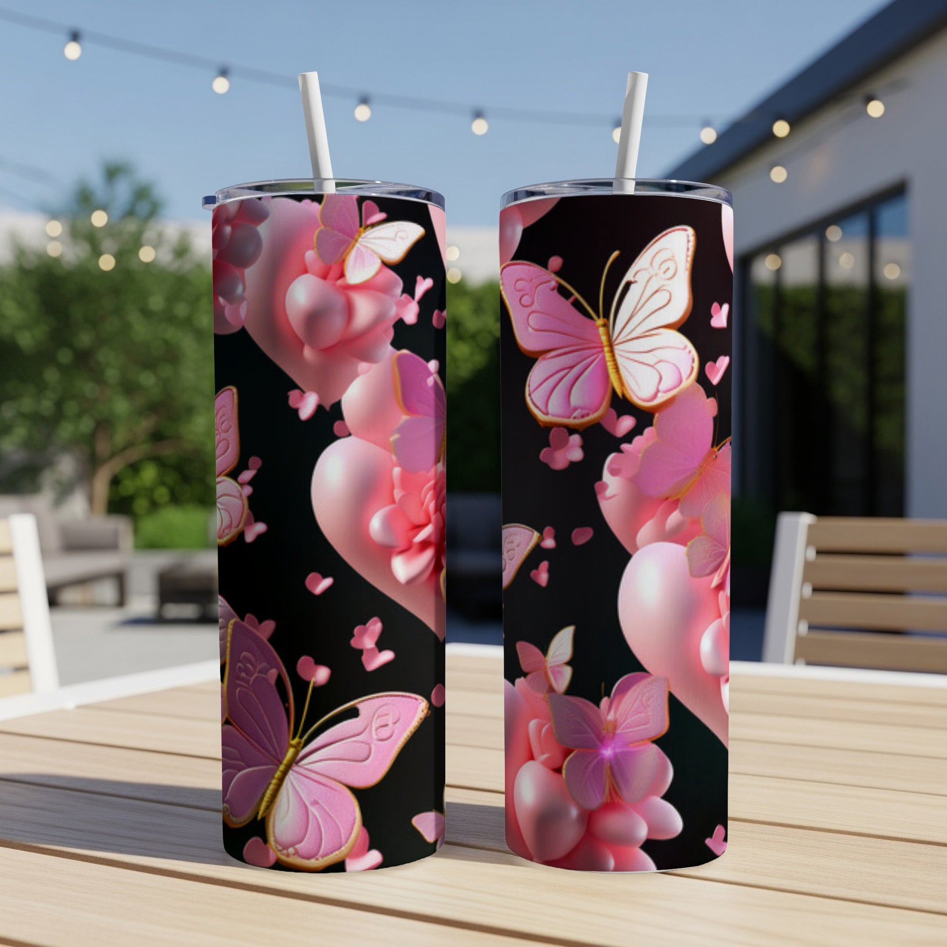 Two tumblers with pink butterflies and heart designs on a table.
