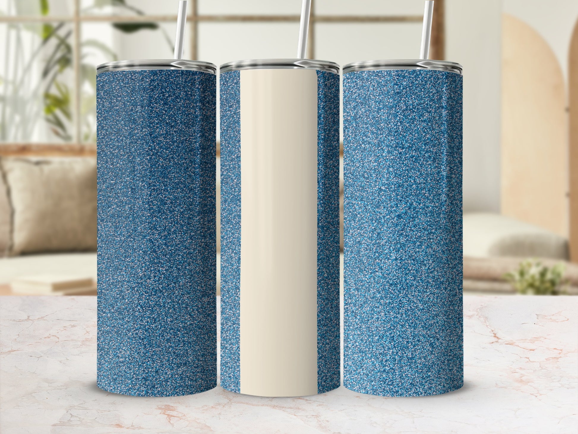 Three glittery blue tumblers with beige centers displayed on a marble surface.