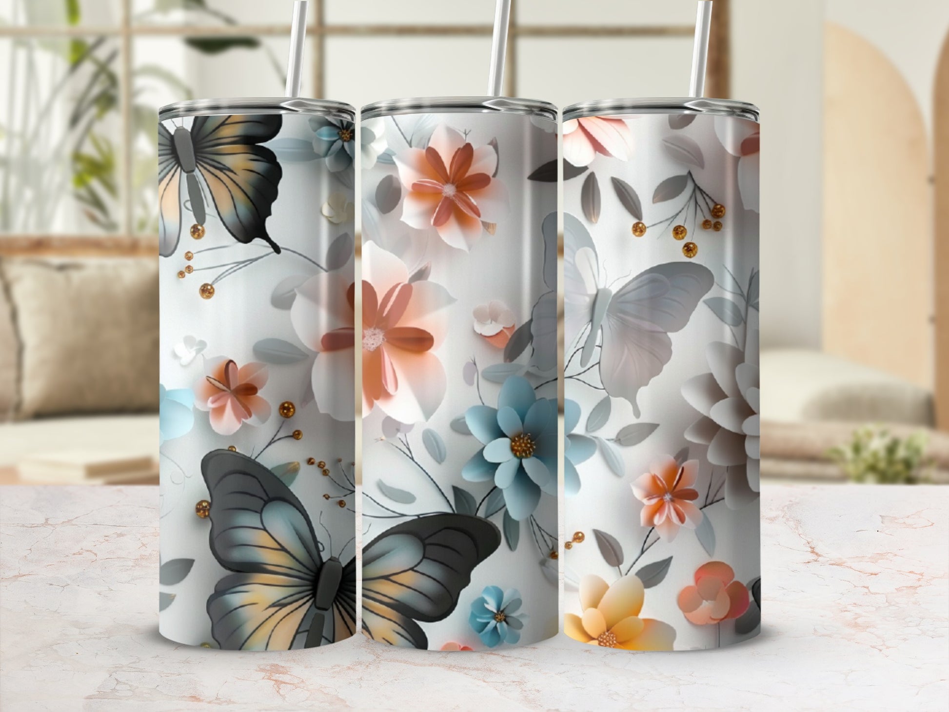 Three tumblers with butterflies and floral designs on a marble countertop.