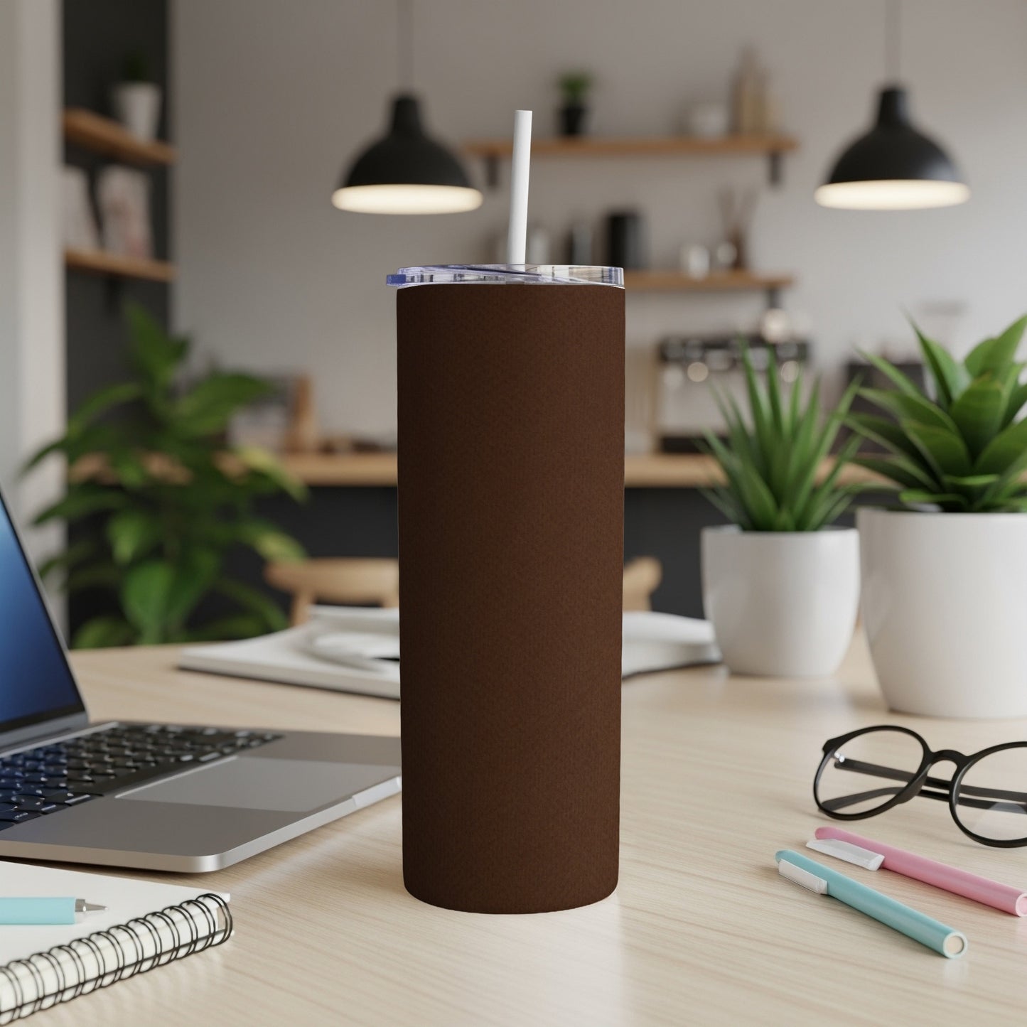 Brown 20 oz skinny tumbler with white straw on a desk with laptop and pens.