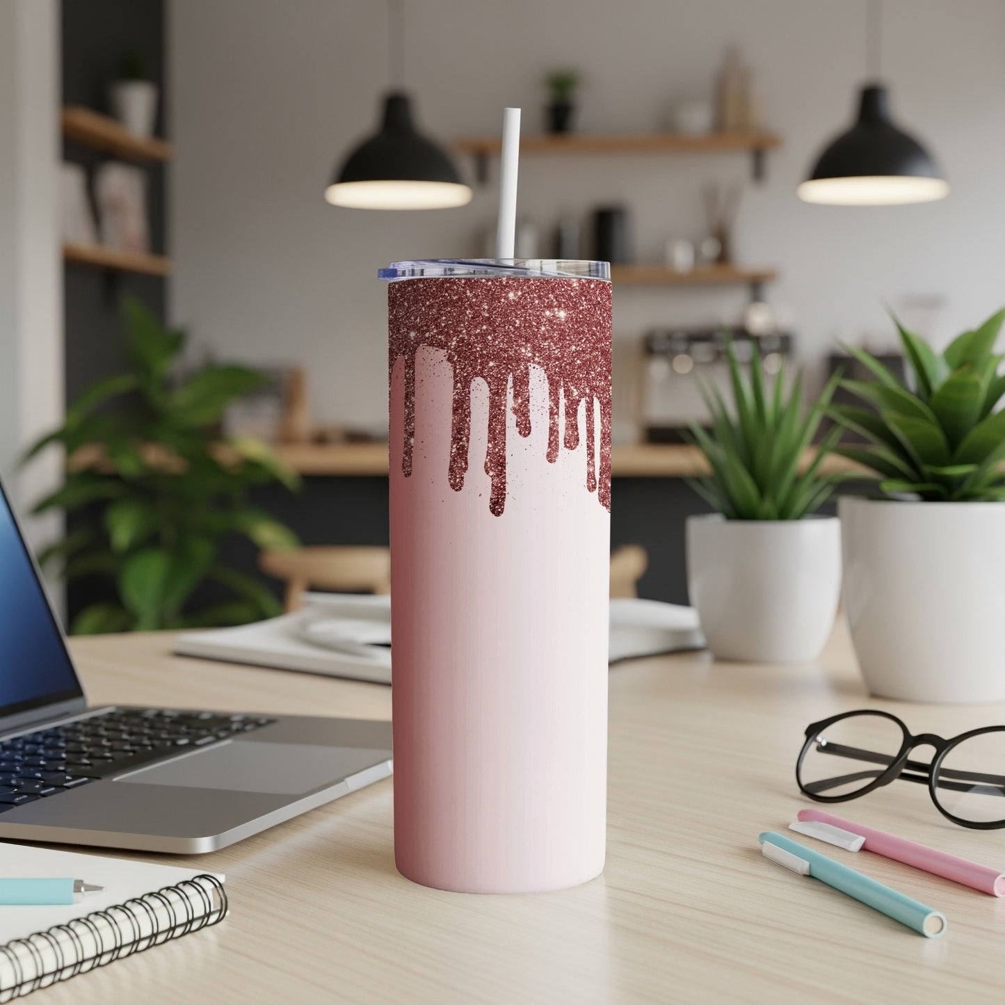 Pink glitter drip tumbler with white straw on a desk next to a laptop