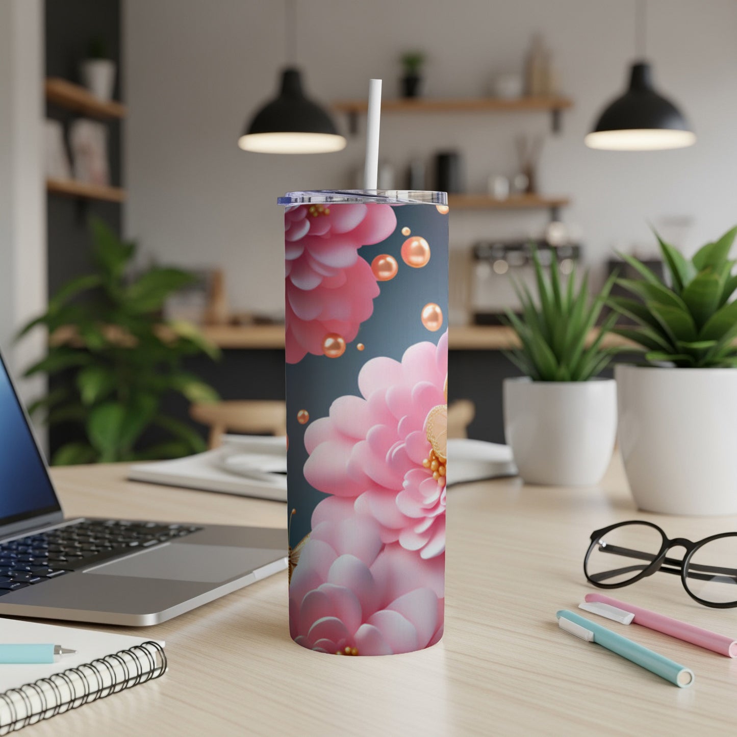 Tumbler with pink floral design and gold bead accents on a desk.