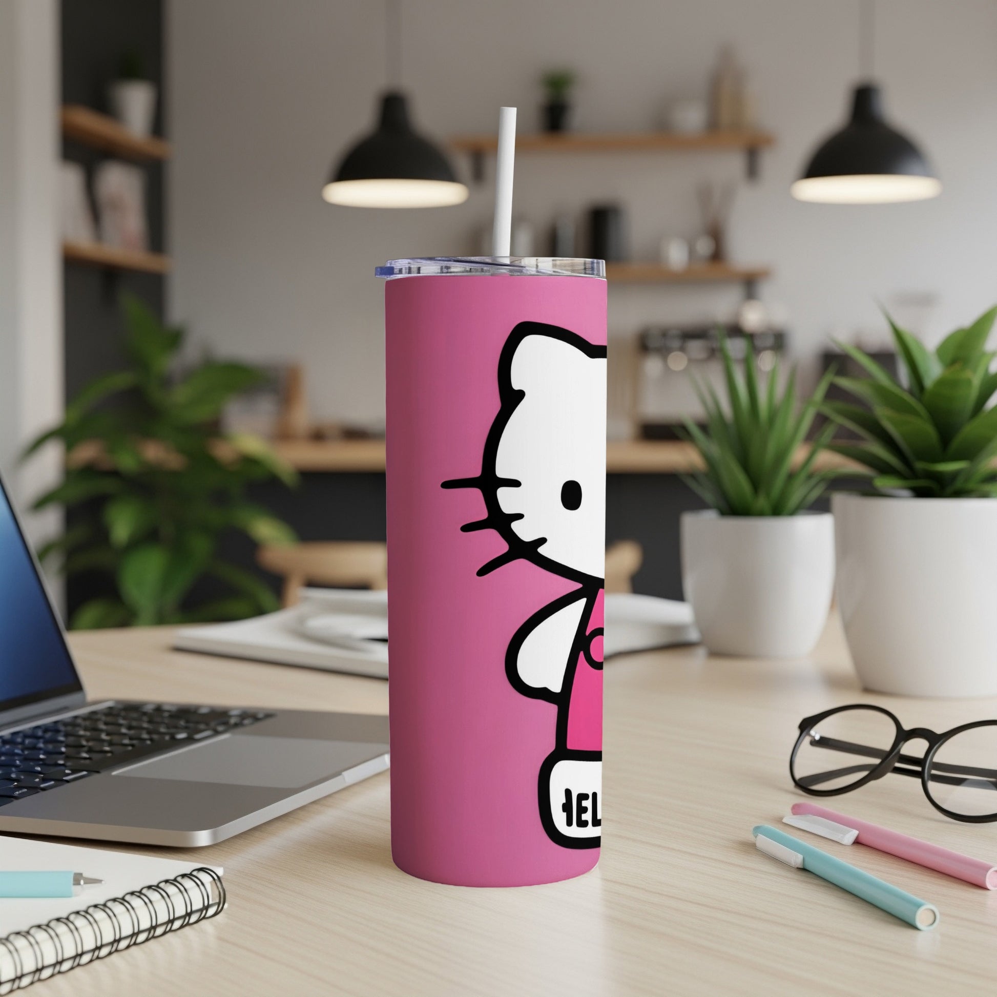 Pink Hello Kitty tumbler with straw on a desk with laptop and pens.