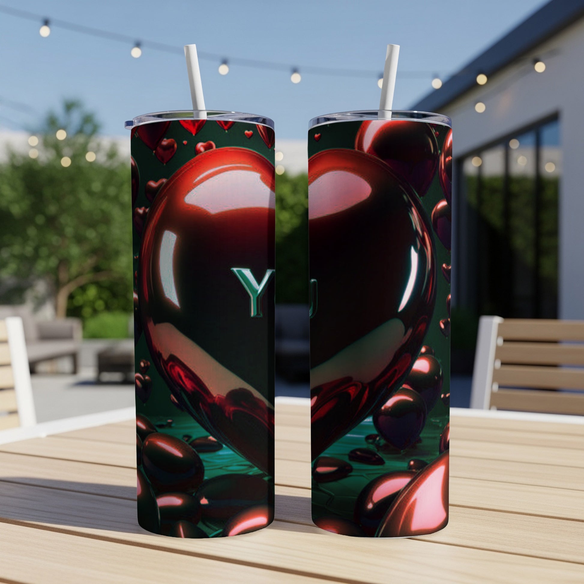 Two tumblers with shiny red hearts and "YOU" text on outdoor patio table.