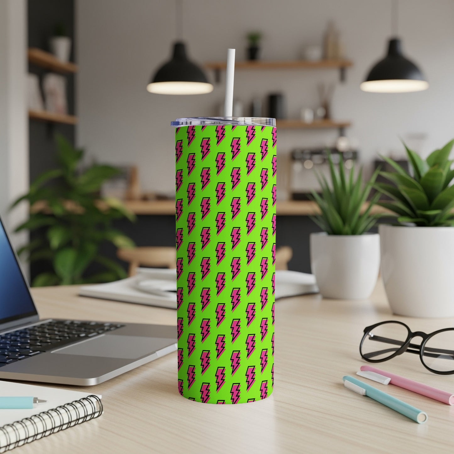 Green tumbler with pink lightning bolt pattern and white straw on desk.