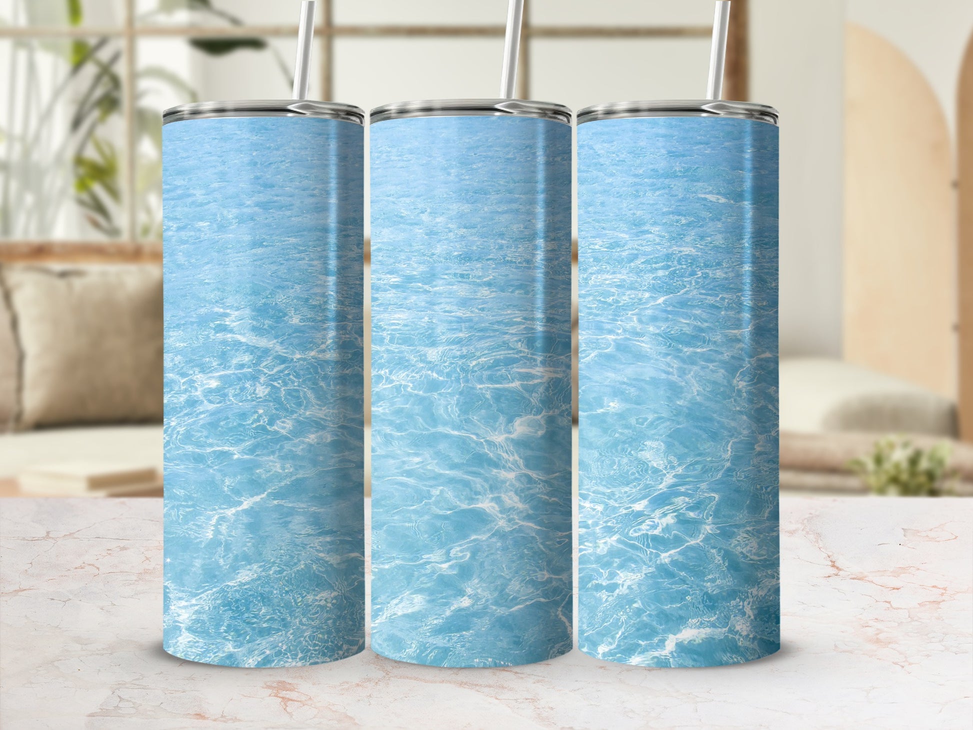 Three tumblers with rippling blue water design on a marble surface.