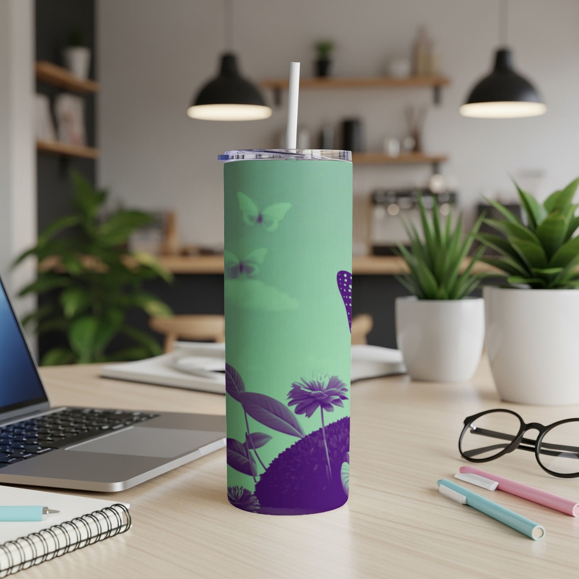 Green tumbler with purple floral and butterfly design on a desk.