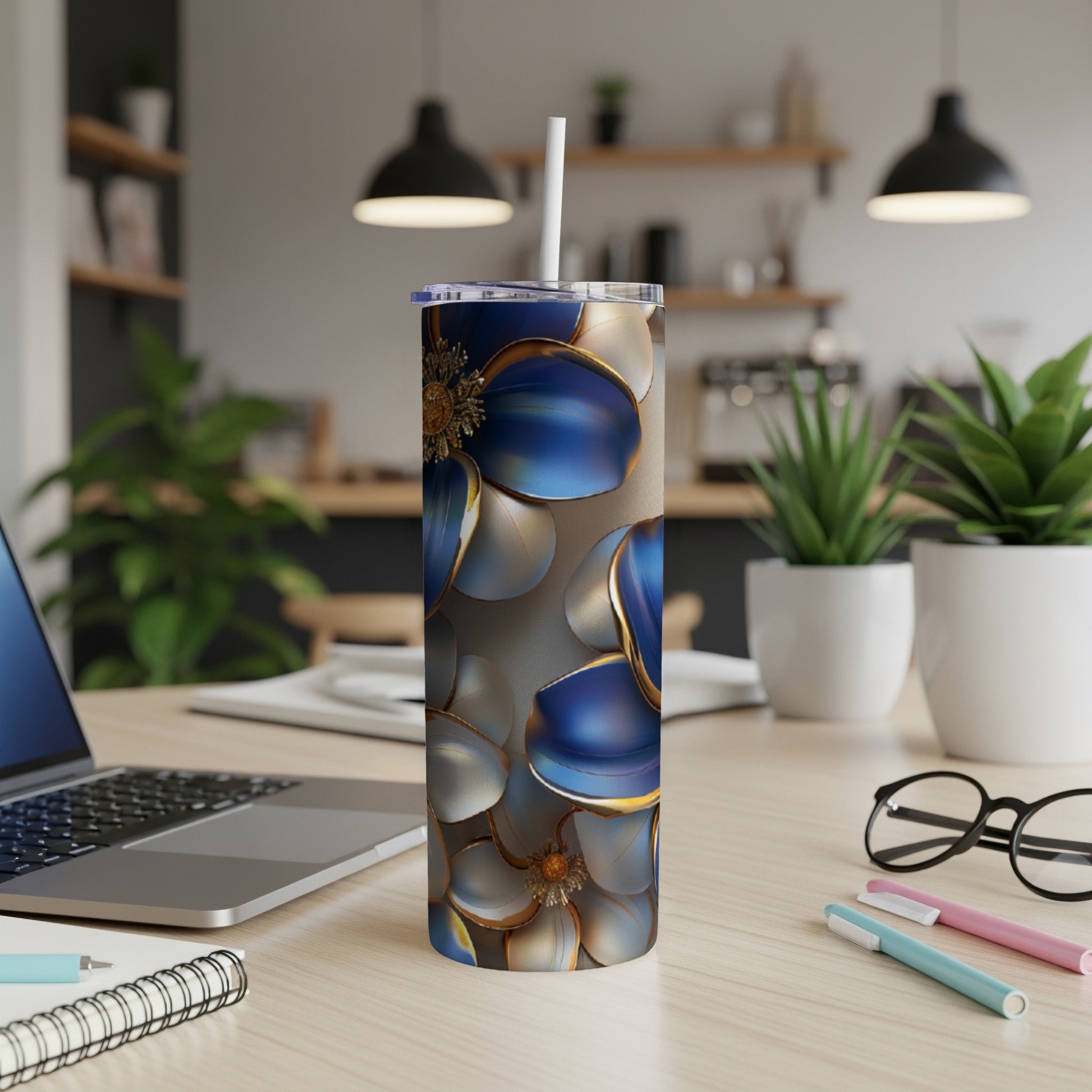 Floral tumbler with blue and gold petals on a desk.