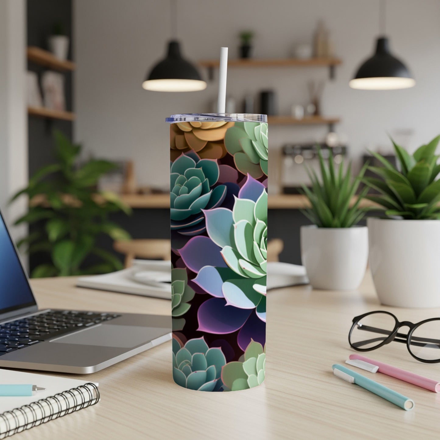 Tumbler with colorful succulent plant pattern on a desk with laptop.