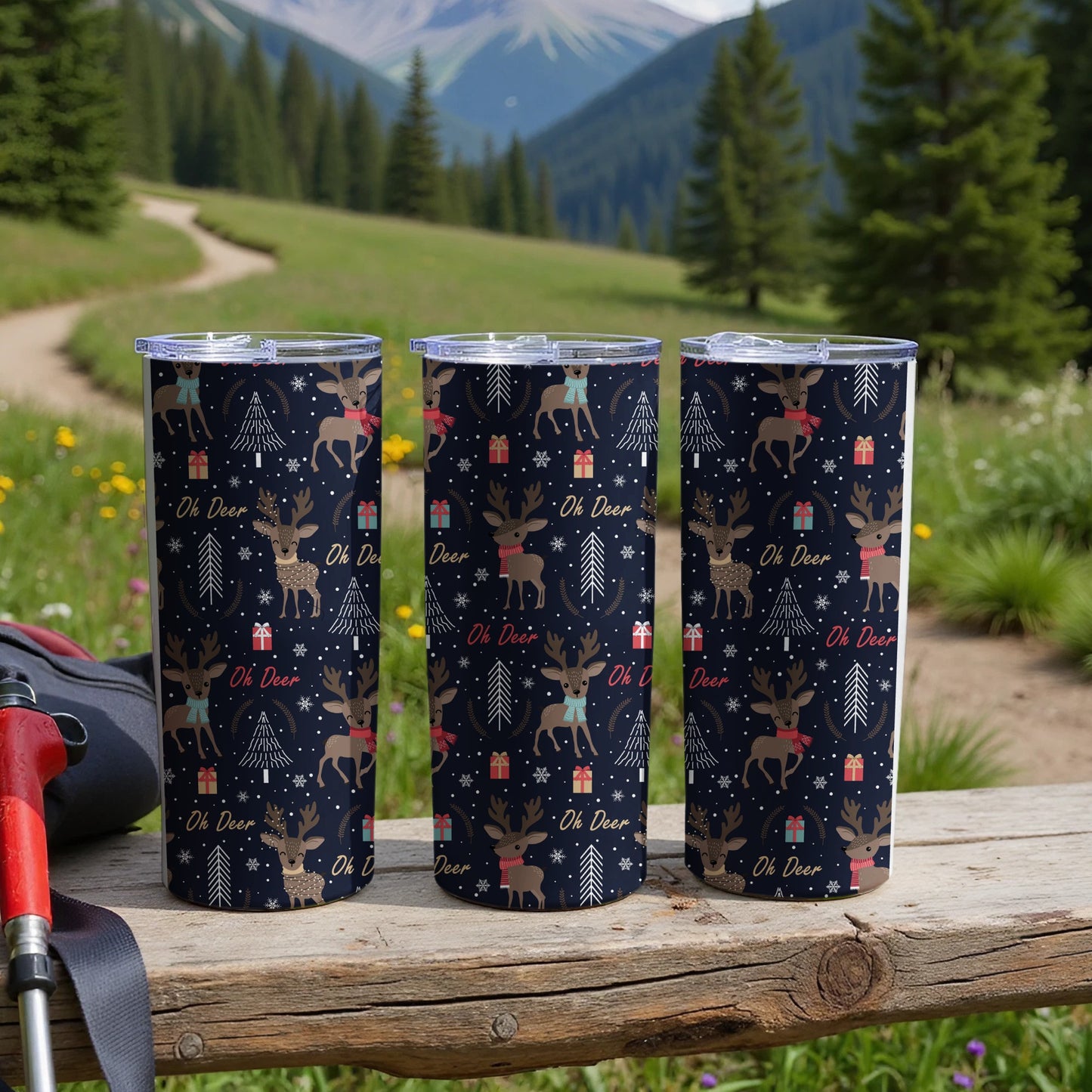 Three tumblers with a deer and snowflake pattern on a wooden surface.