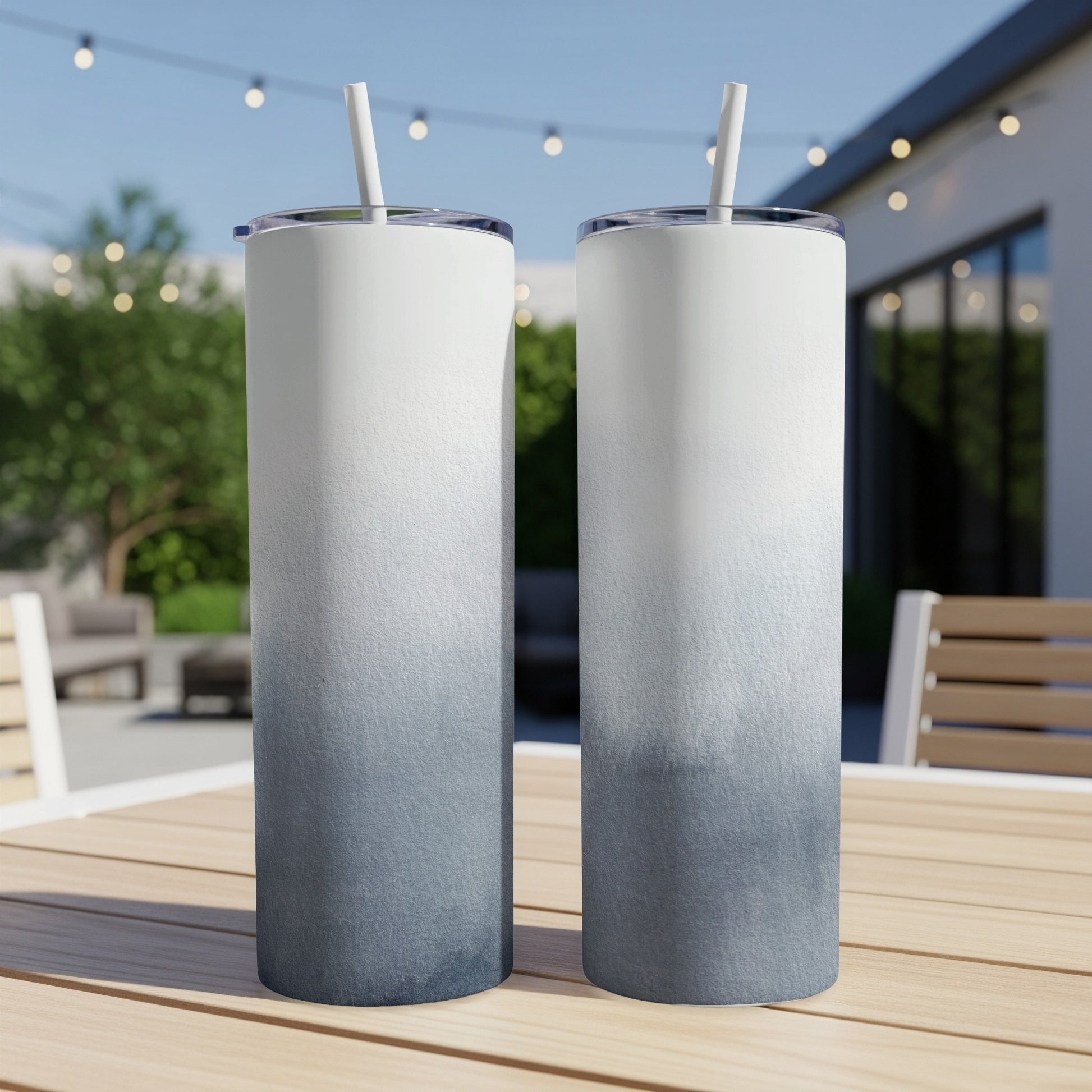 Two tall tumblers with a blue-to-white ombre design on a wooden table.