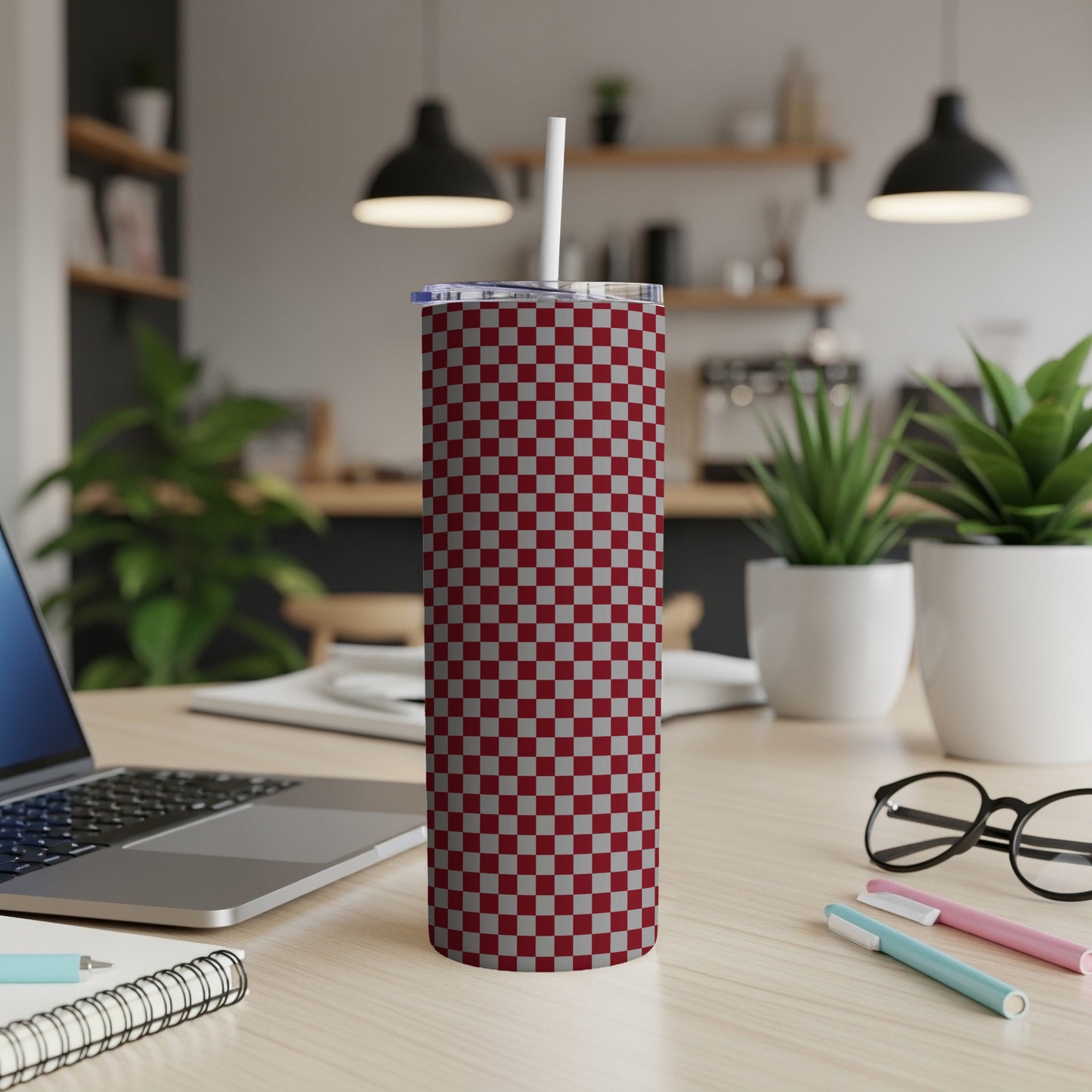 Red and gray checkered pattern stainless steel tumbler with white straw on desk.