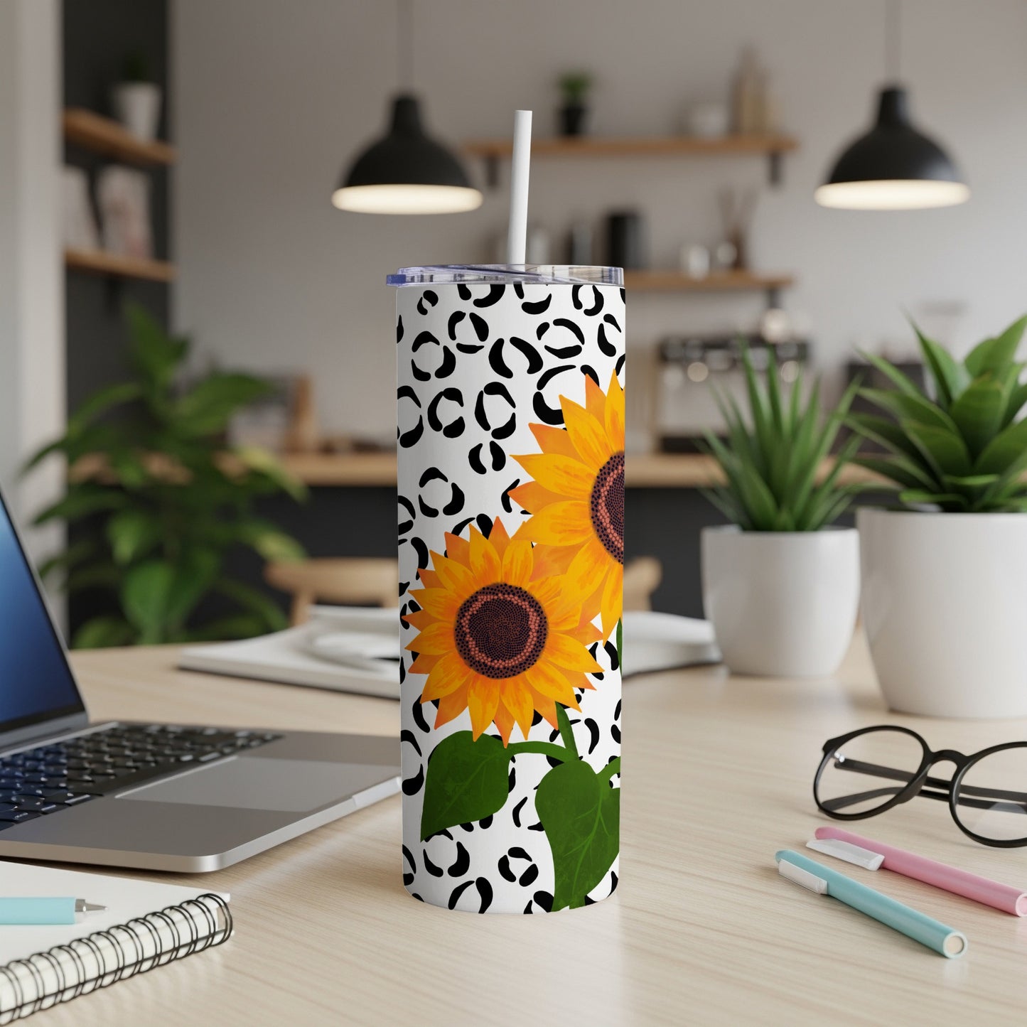 Tall tumbler with sunflowers and leopard print on desk.