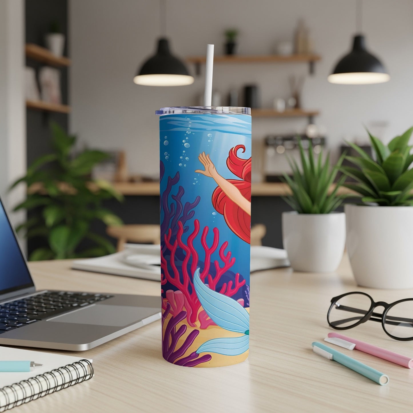 Ariel the mermaid swims in colorful coral reefs, with a straw in her tumbler.