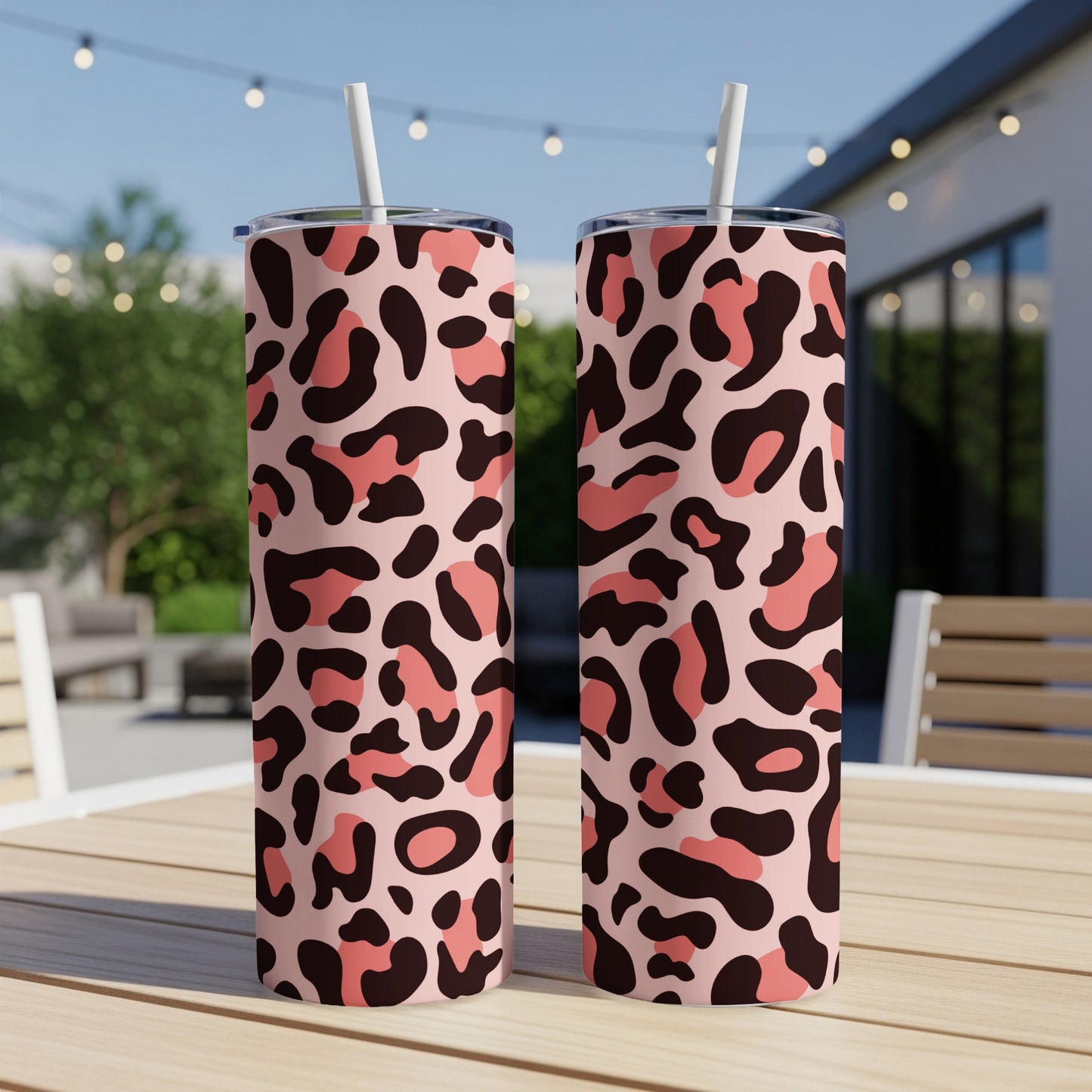 Two tall tumblers with pink and brown leopard print pattern stand on a wooden table.