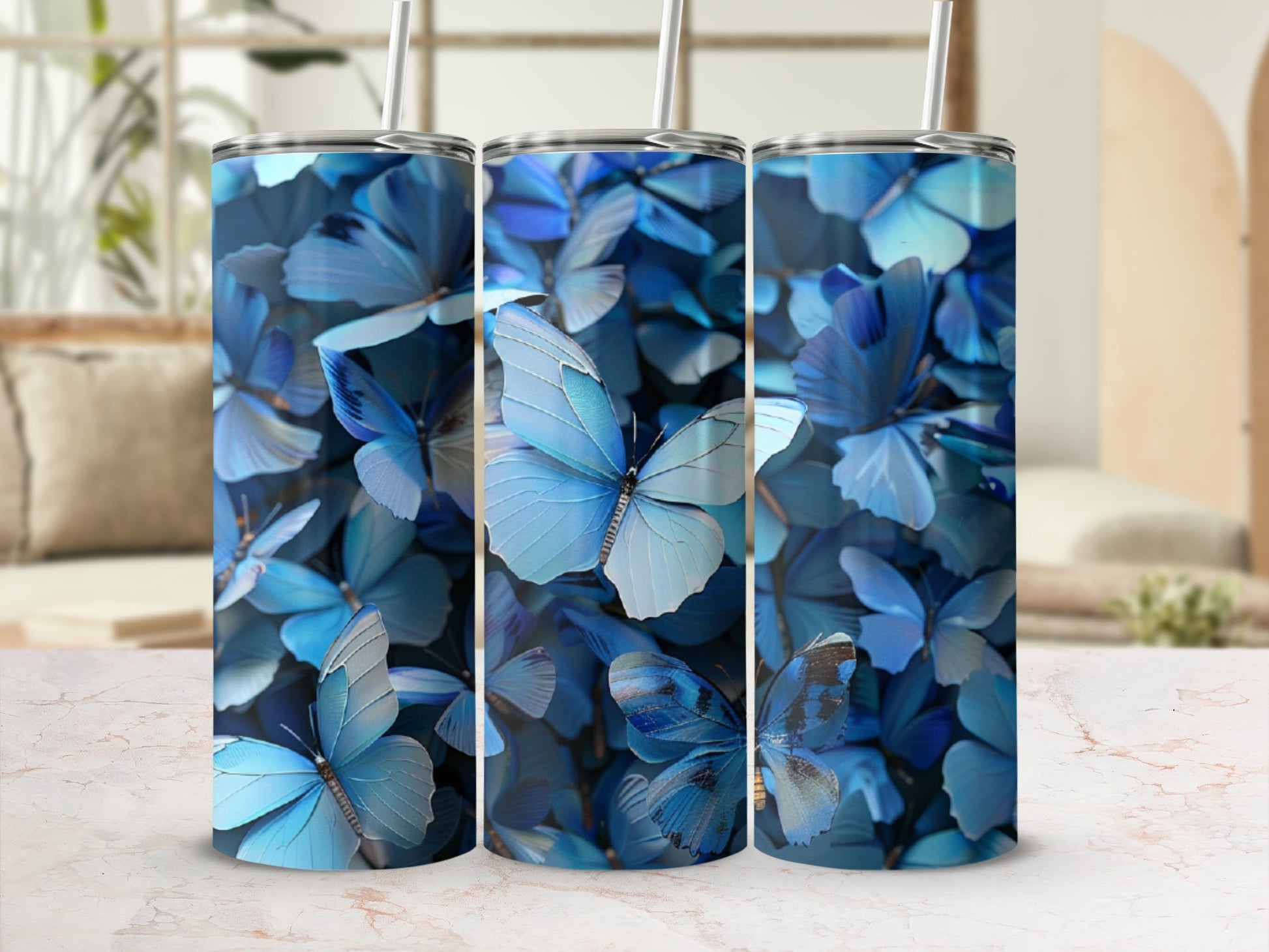 Three blue butterfly pattern tumblers on a marble surface.