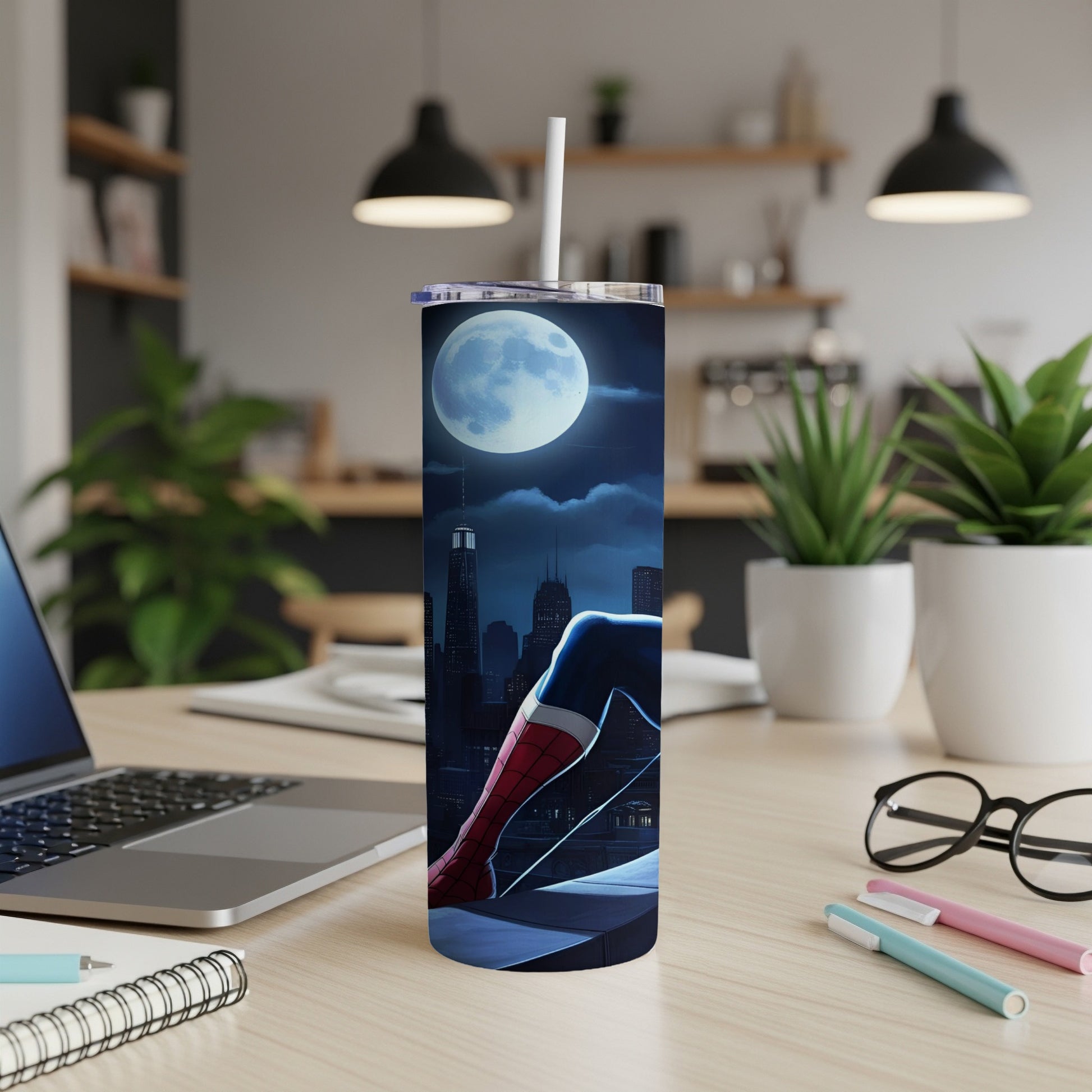 Superhero tumbler with moonlit cityscape and character legs on desk.