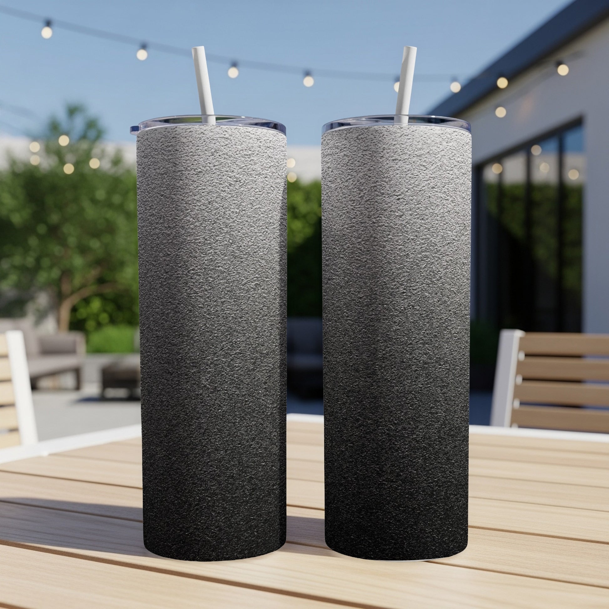 Two tall tumblers with a black to white gradient design on a wooden table.