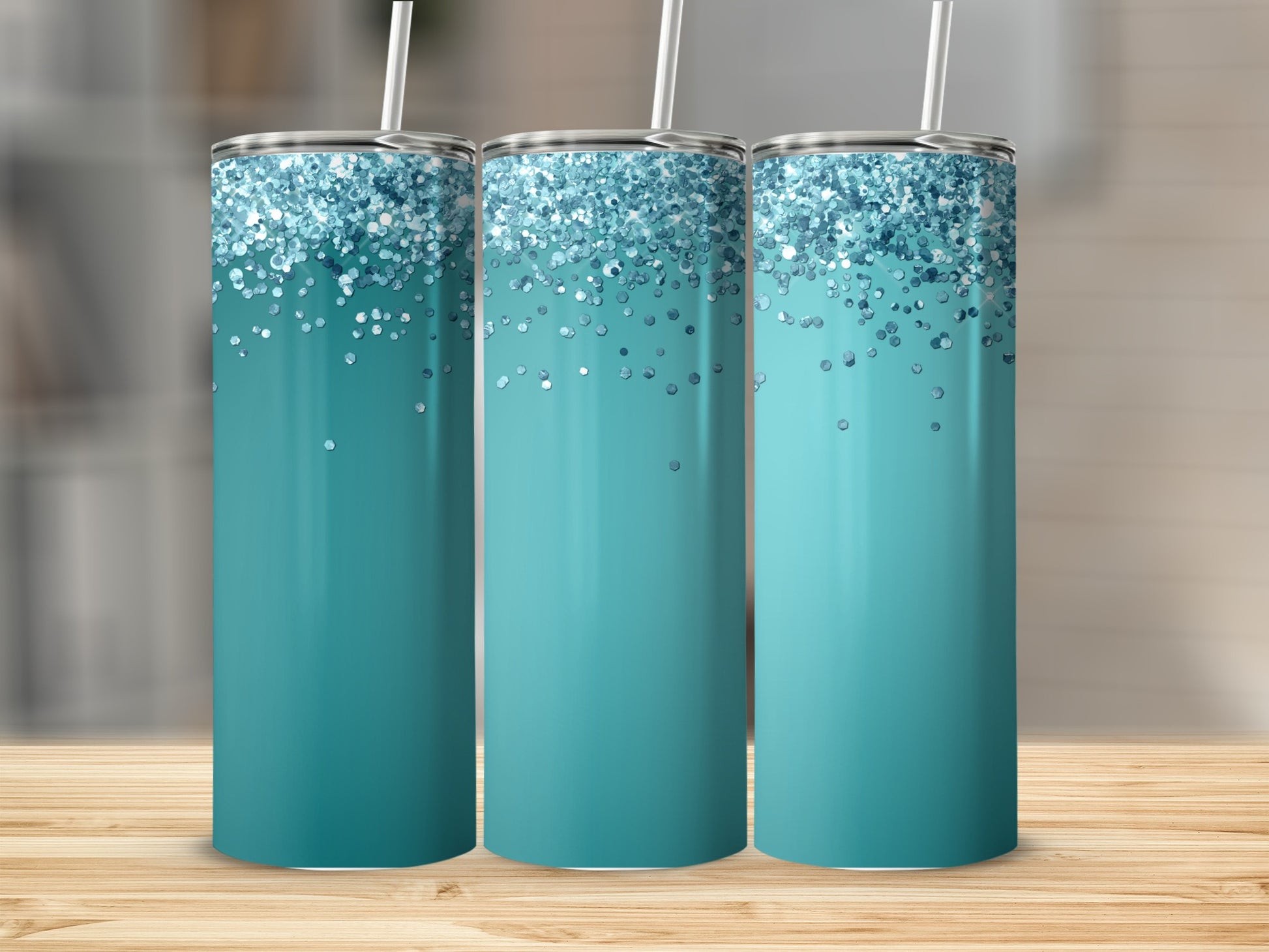 Three teal tumblers with glitter accents and straws on a wooden surface.