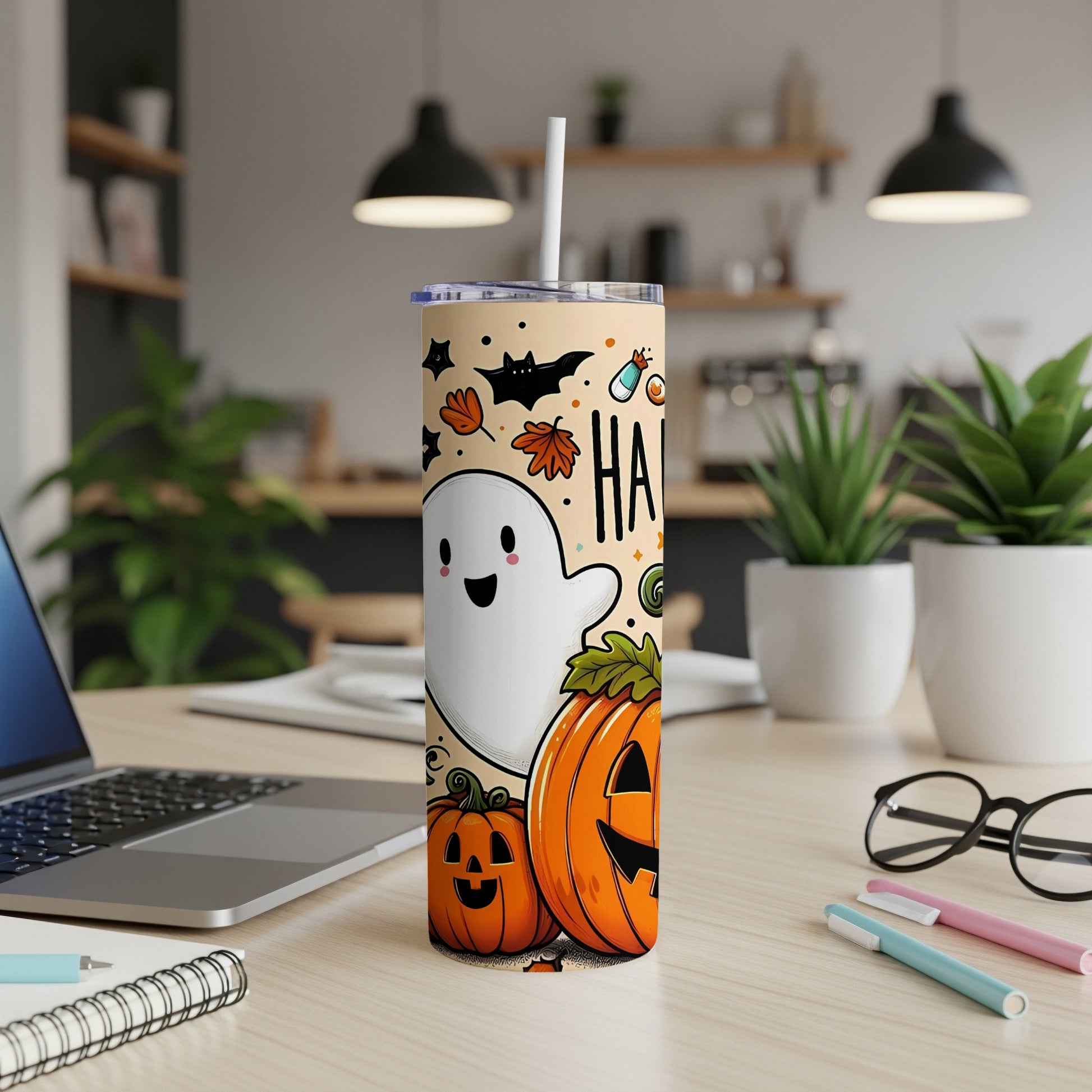 Halloween tumbler with ghost, bats, pumpkins, and "HAA" text on a desk.