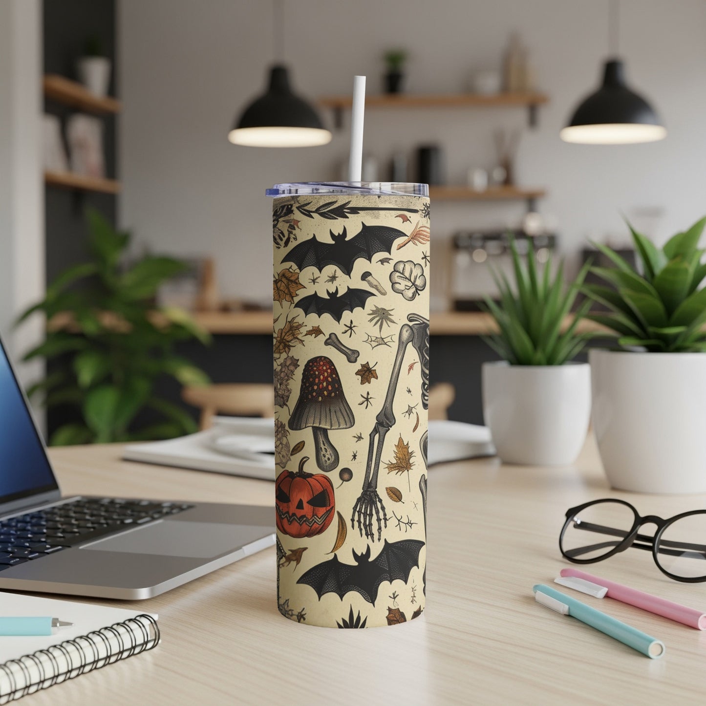 Halloween themed tumbler with bats, skeletons, mushrooms, and pumpkins on a light background.