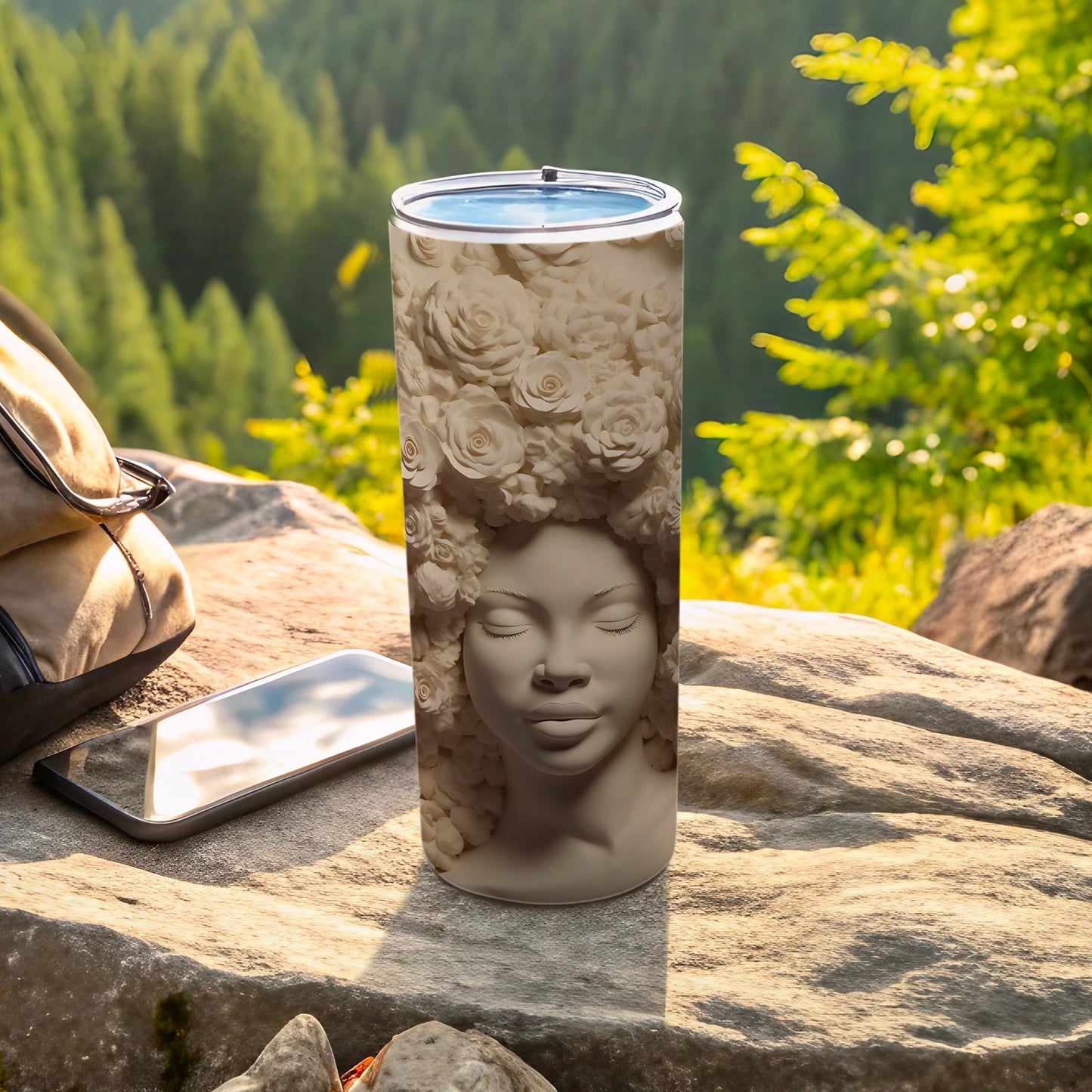Sculpted tumbler with a woman's face adorned with roses, resting on rocks.