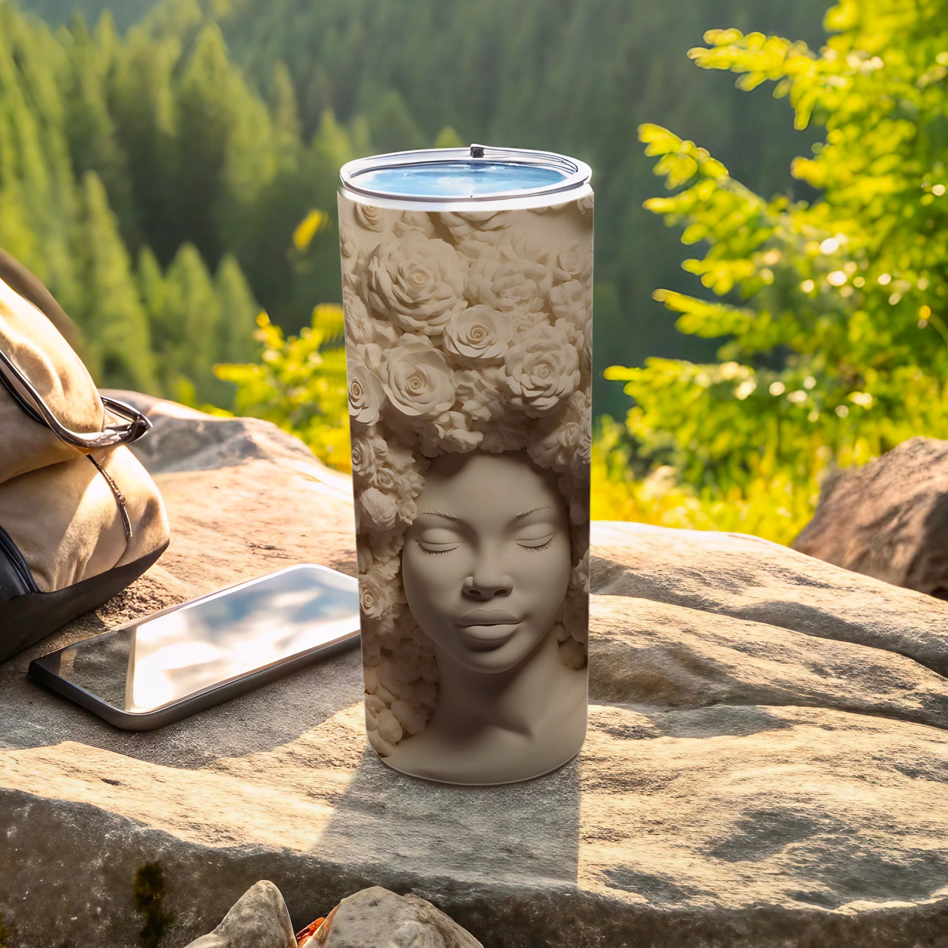 Sculpted tumbler with a woman's face adorned with roses, resting on rocks.