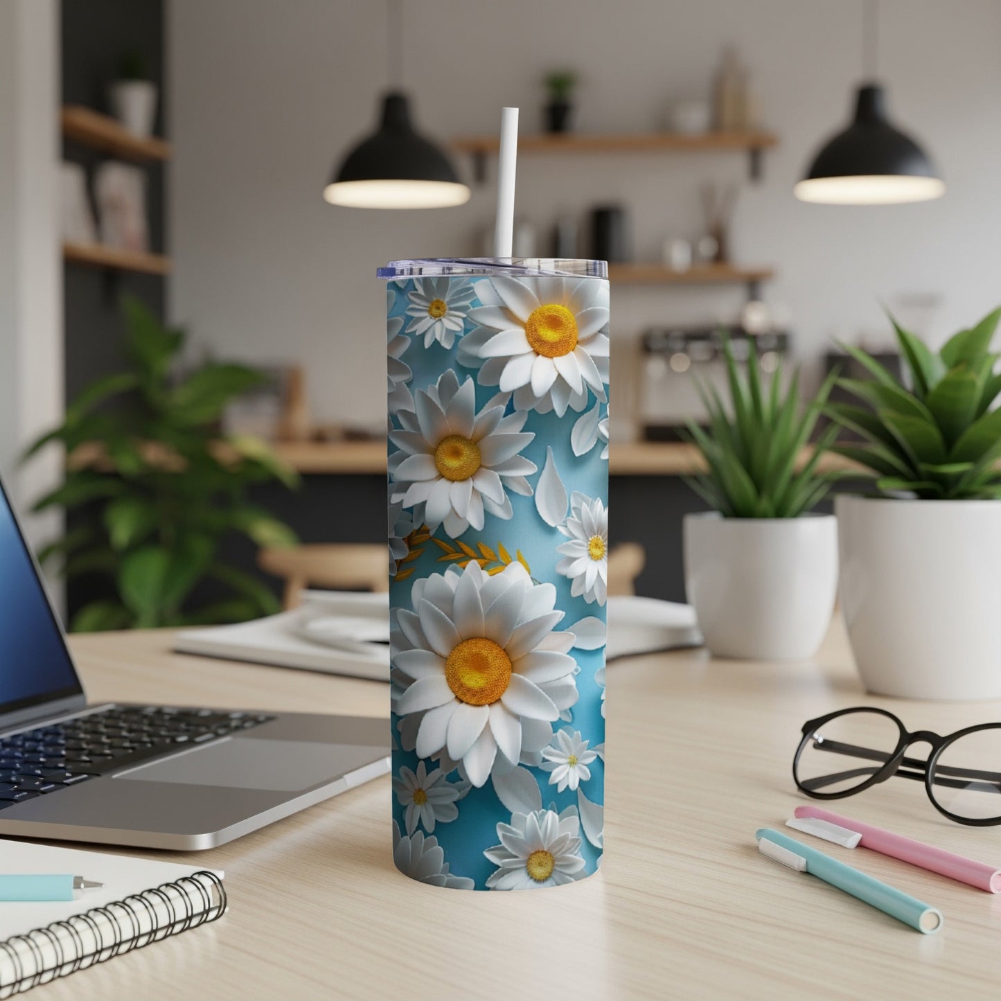 Blue tumbler with white daisies and green leaves.